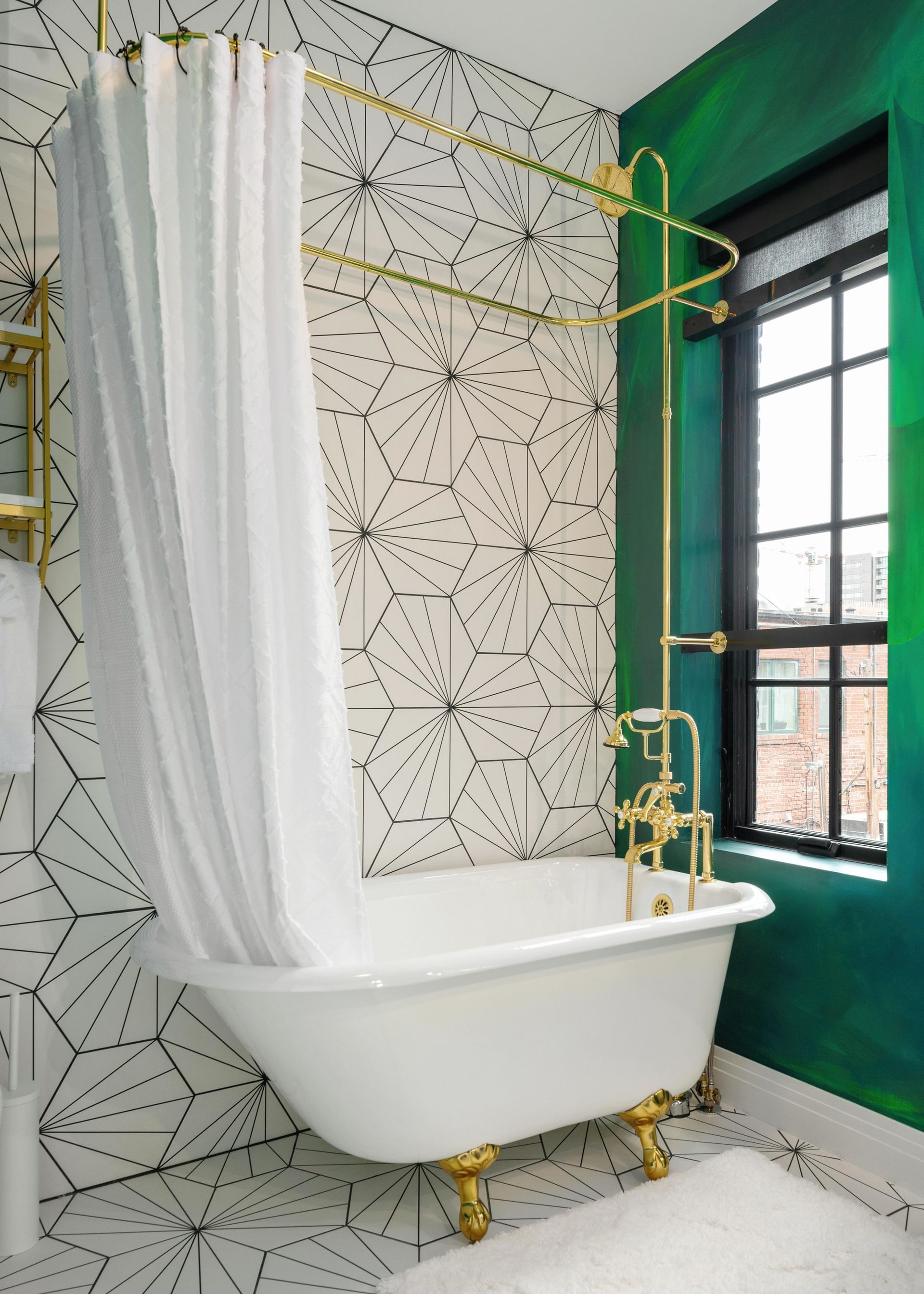 Bright bathroom with a white clawfoot tub, gold fixtures, green walls, and patterned tile.