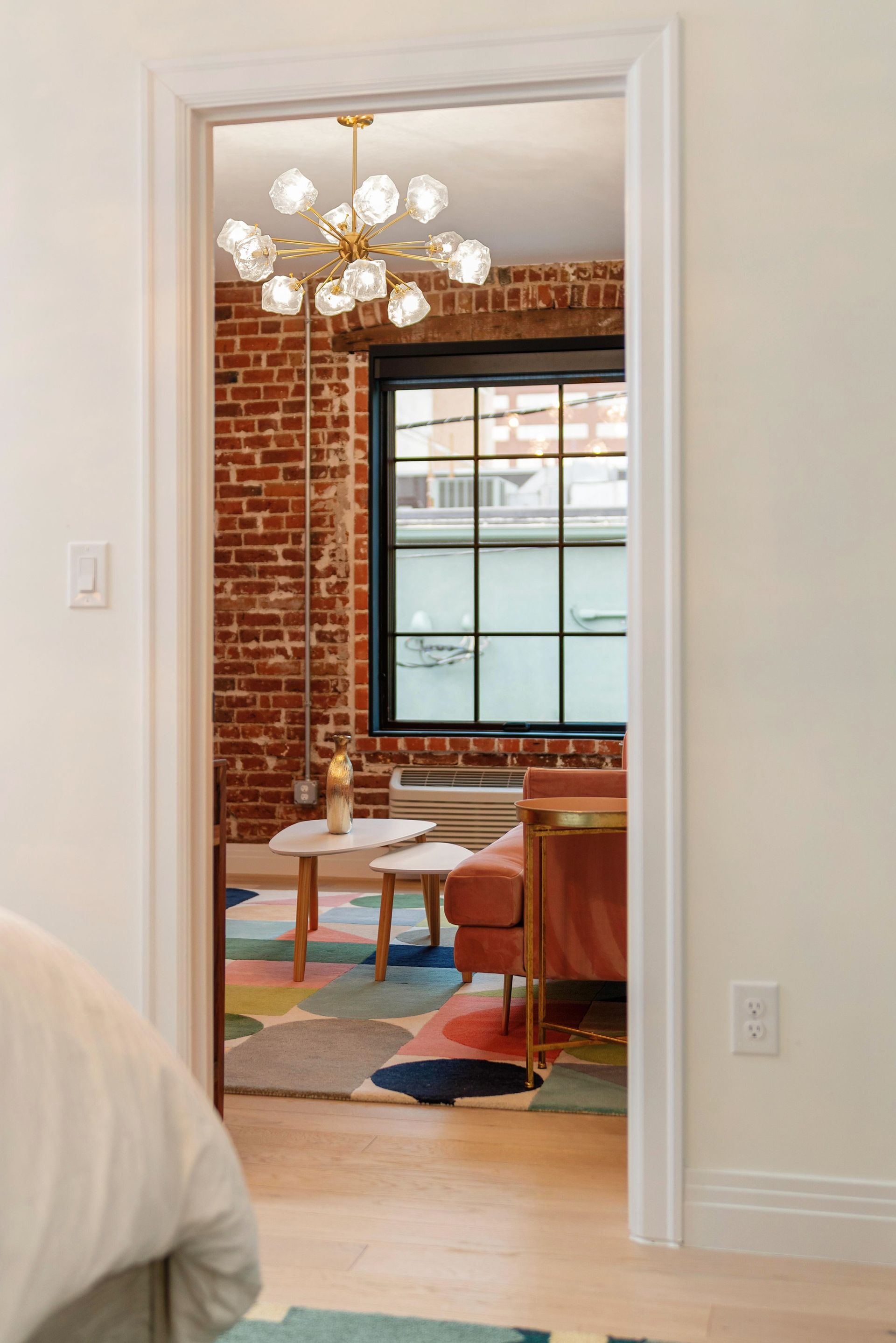 View through a white doorway into a brick-walled dining room with a chandelier, table, and chairs