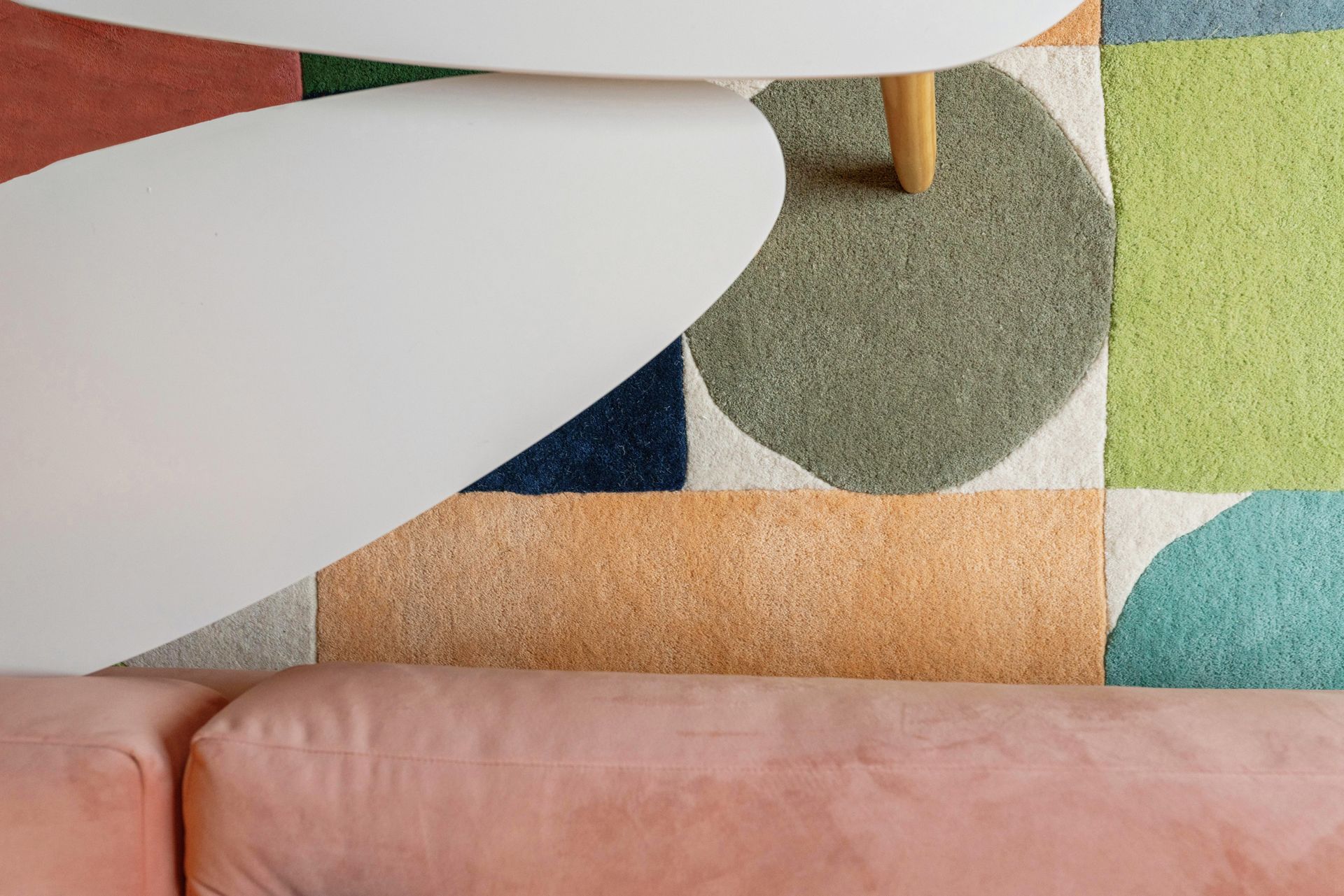 Colorful geometric rug with white chairs and a pink sofa in a modern living room