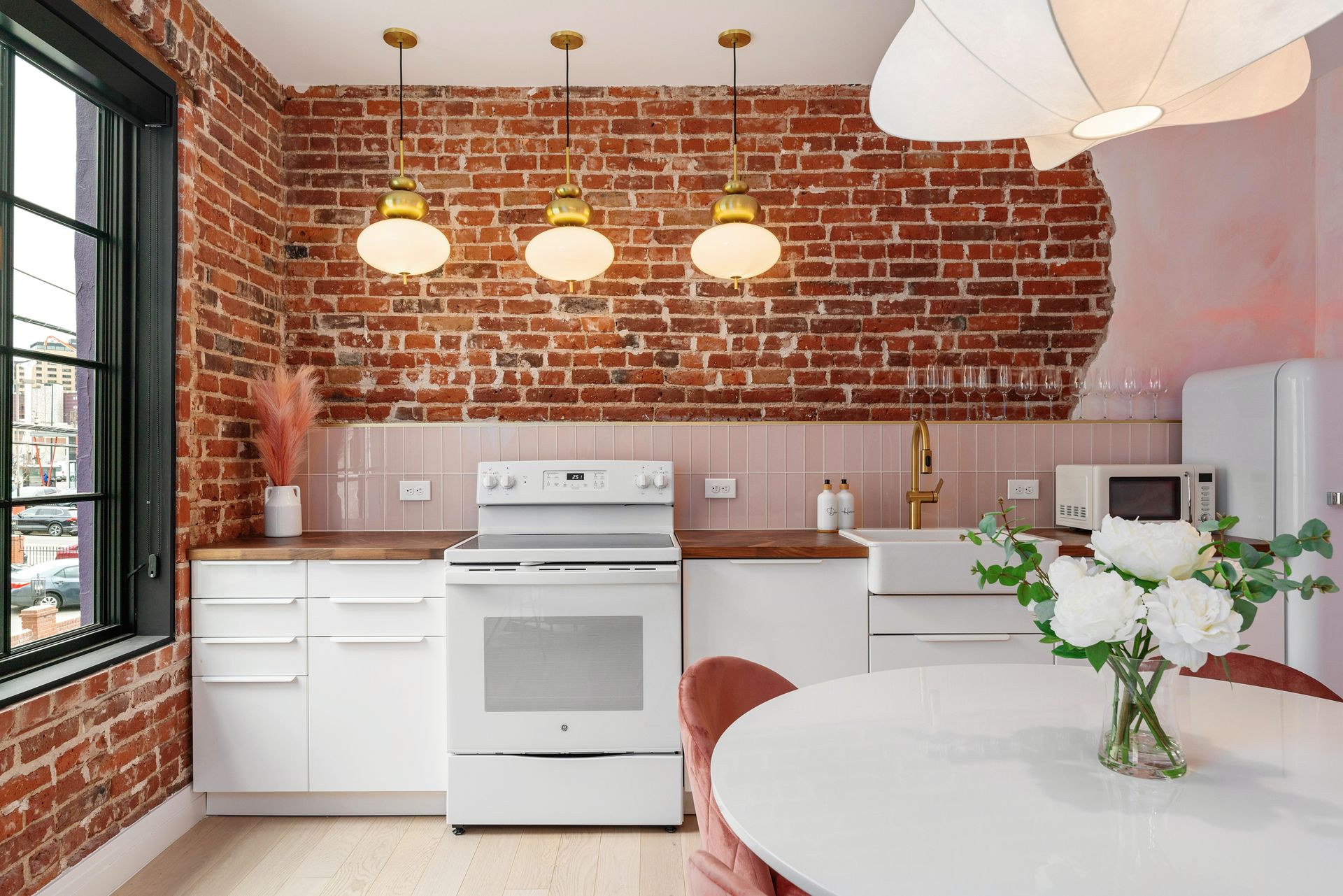 Bright kitchen with white cabinets, brick wall, vintage stove, and round table with flowers