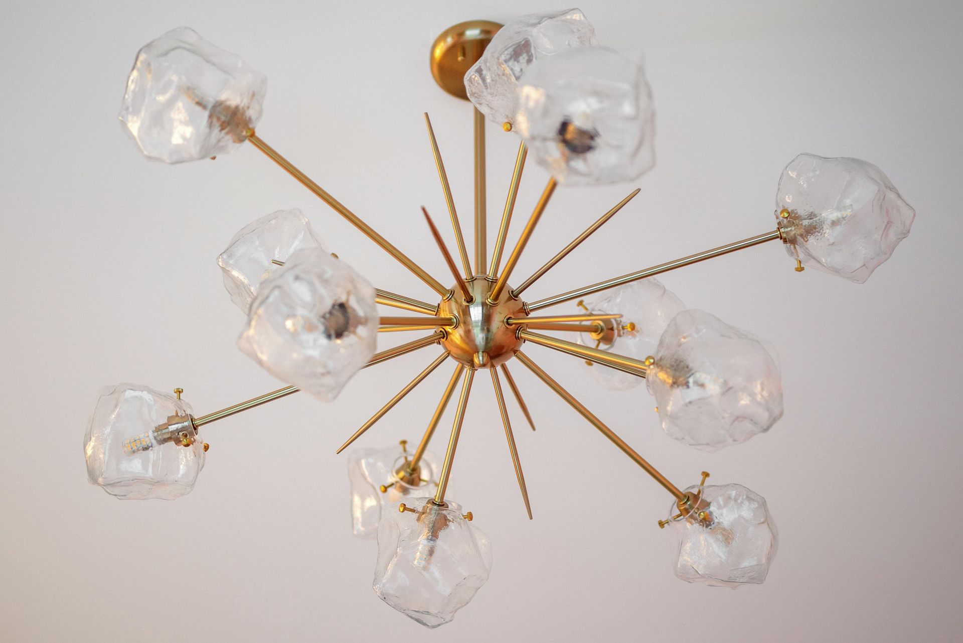 Gold starburst chandelier with clear glass shades on a white ceiling
