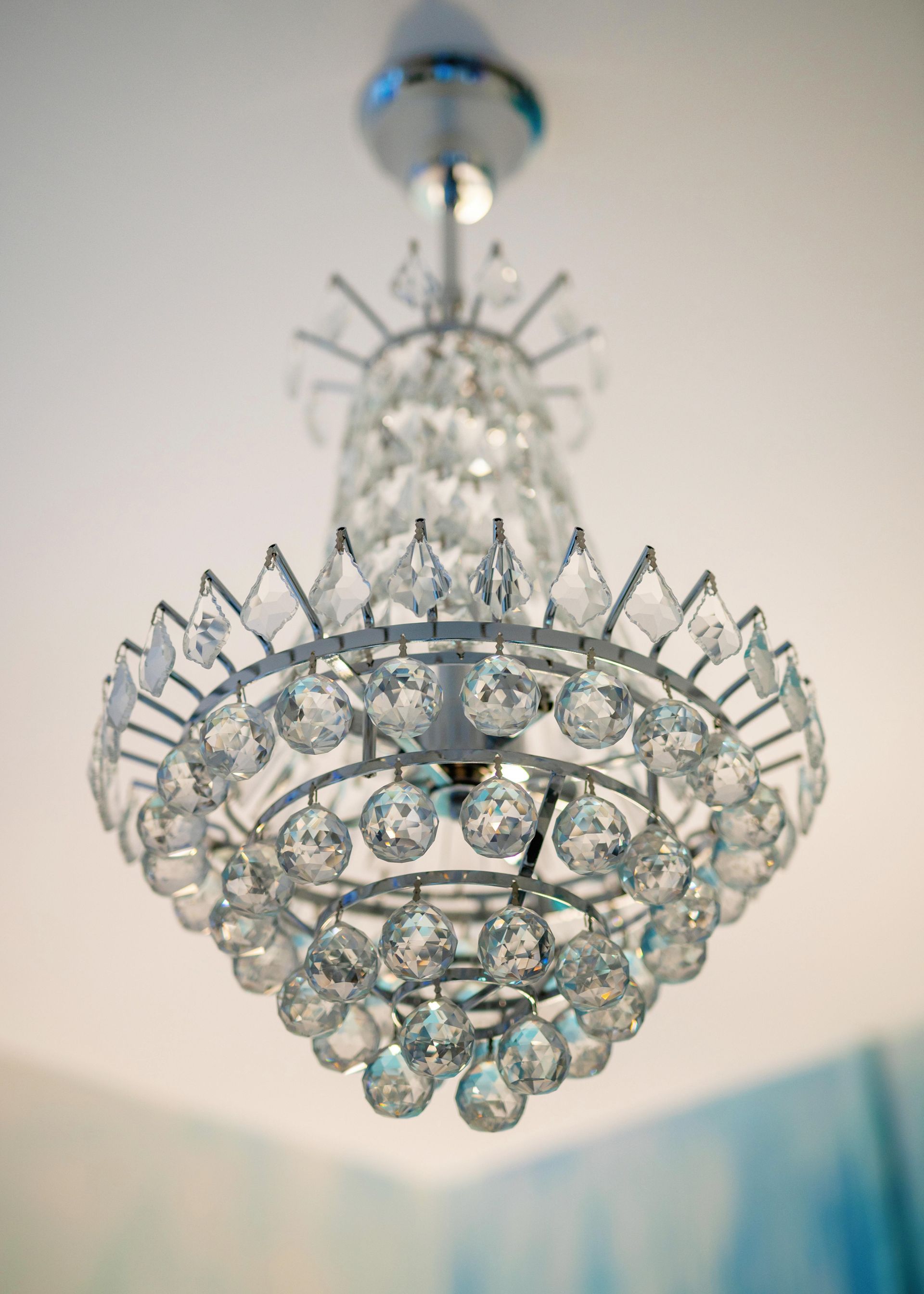 Crystal chandelier hanging from a ceiling, with sparkling clear glass and silver accents.