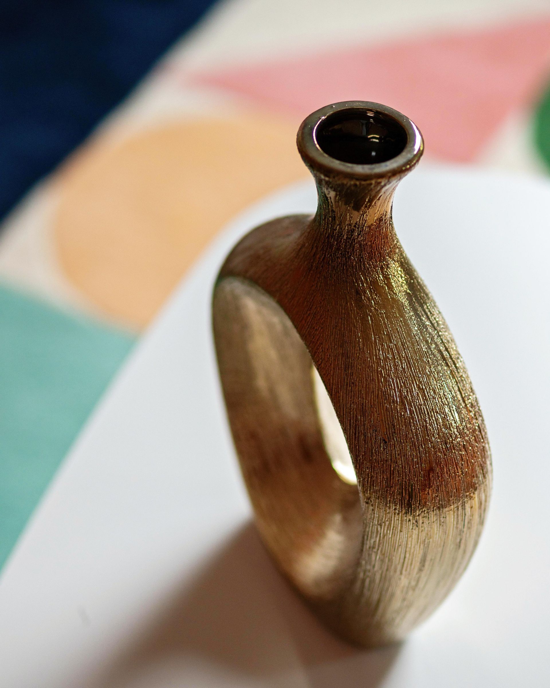 Brown ceramic ring-shaped vase with a narrow neck on a white surface