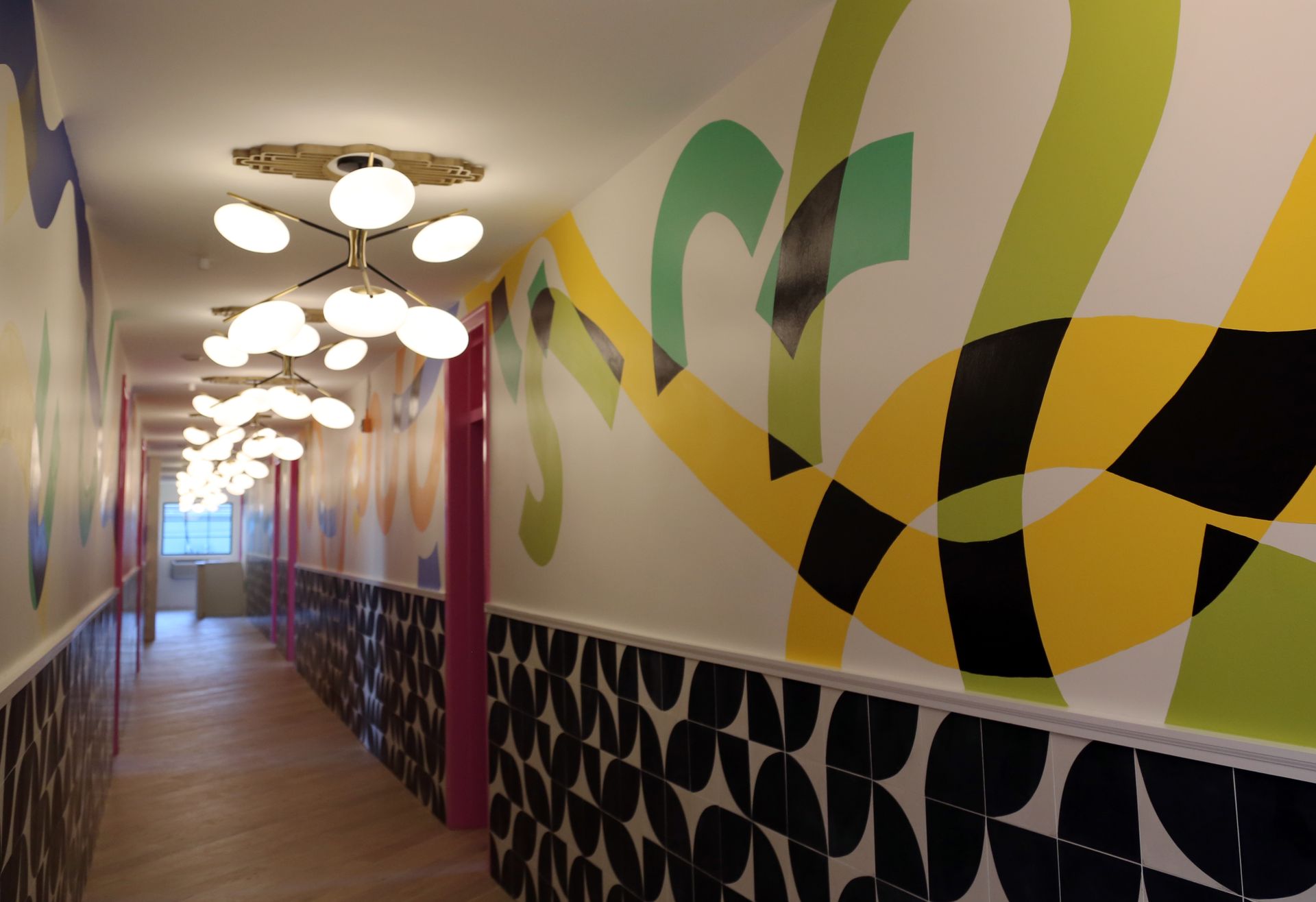 Colorful hallway with abstract mural, pendant lights, and wood floor