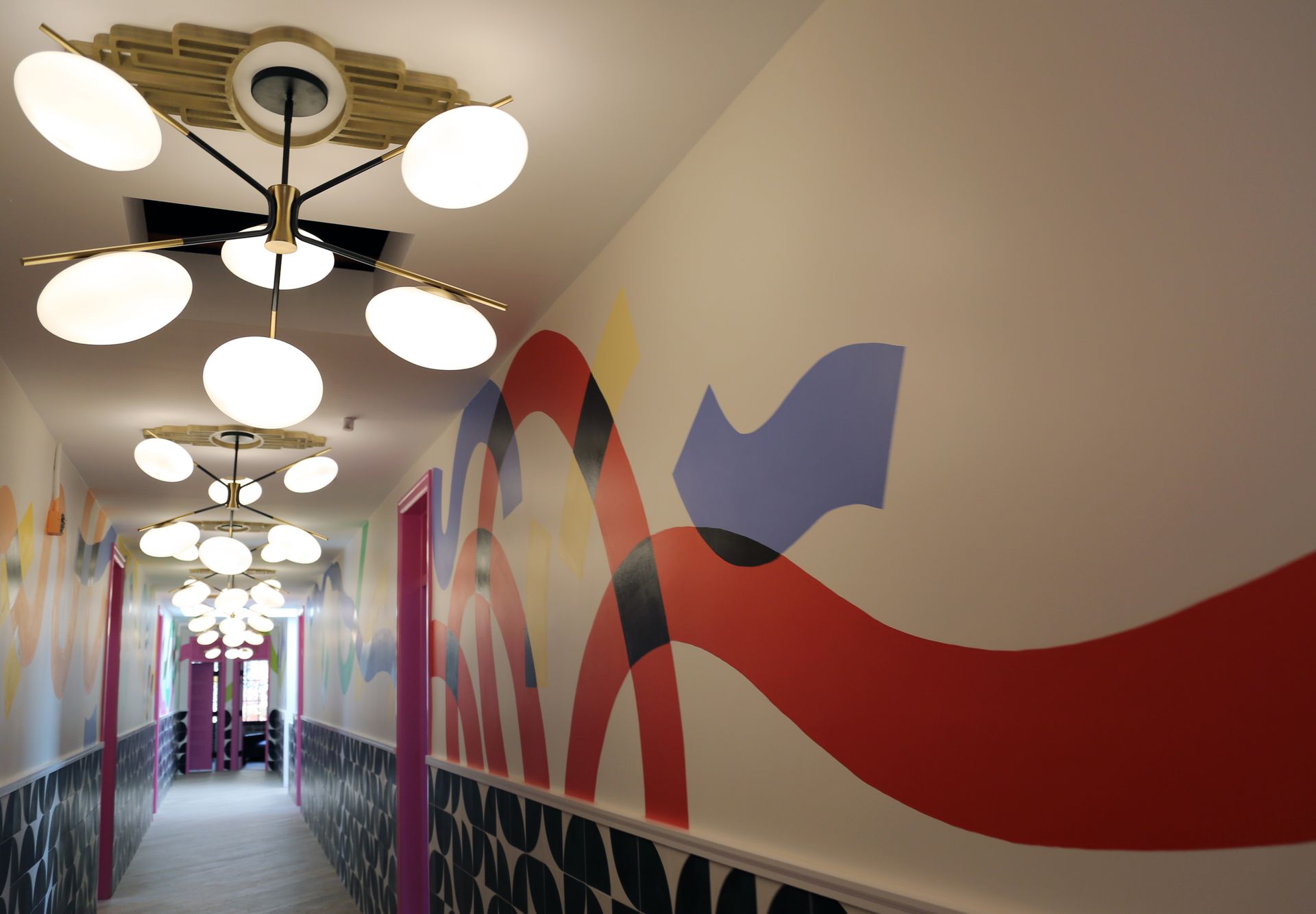 Hallway with round ceiling lights and a colorful wave mural on the wall