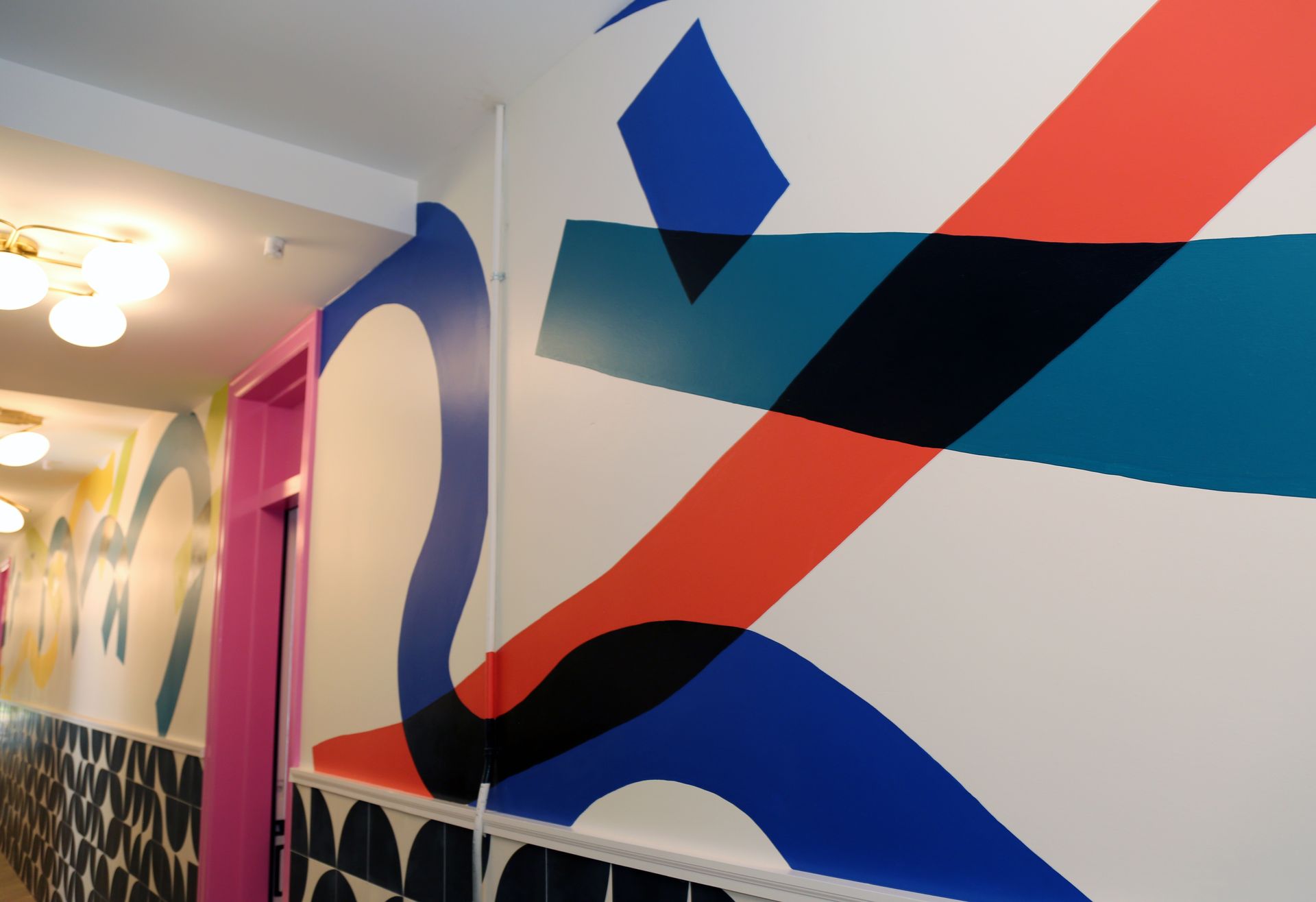 Colorful abstract mural in a hallway with bold blue, red, and black geometric shapes