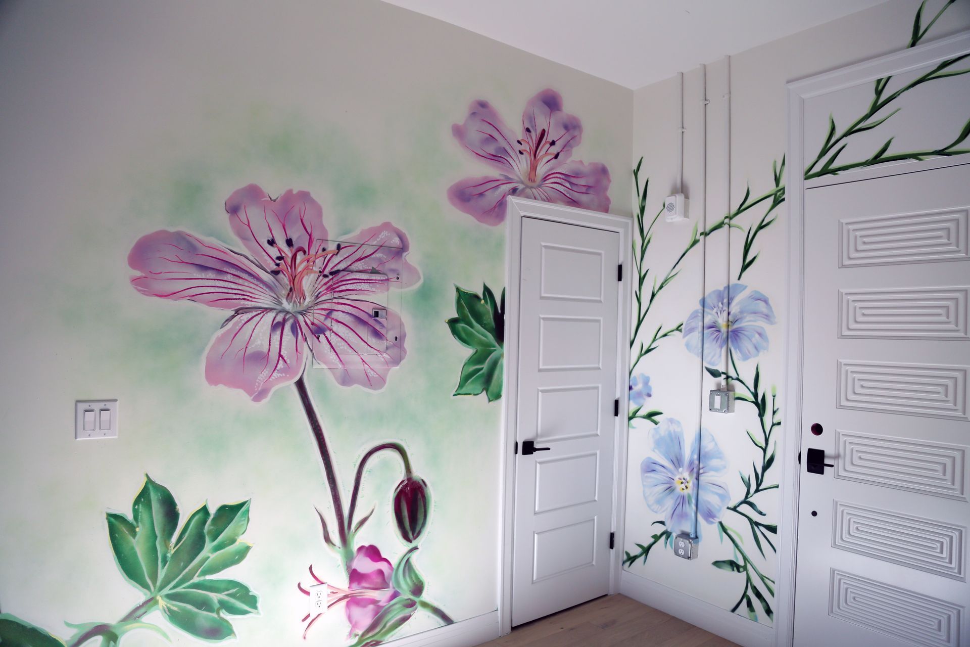 Flower mural painted on white bedroom walls with pink, purple, and blue blossoms