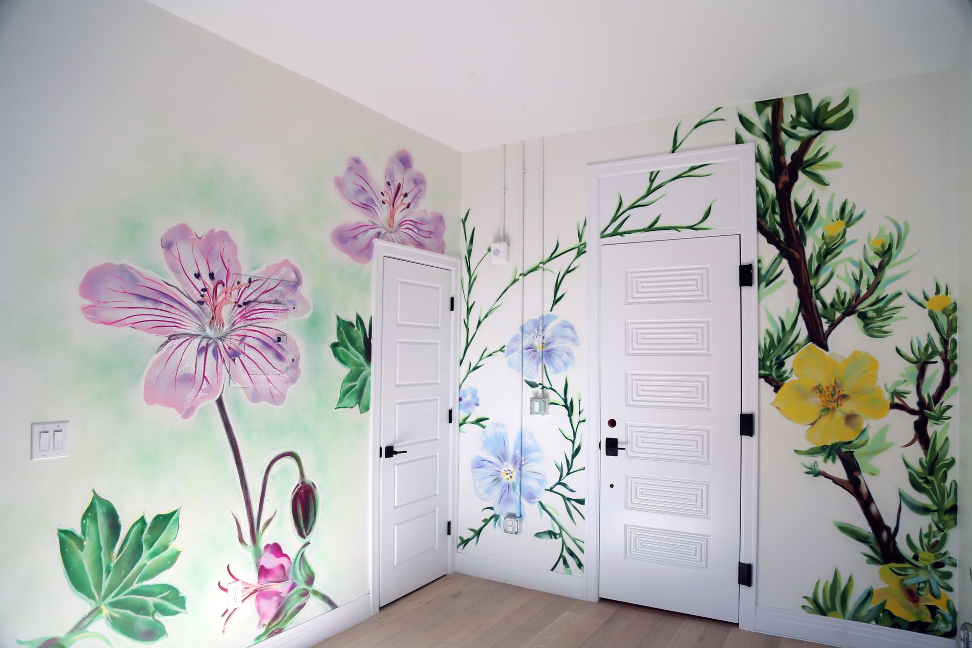 Flower mural on bedroom walls and white closet doors, with pink, blue, and yellow blooms.