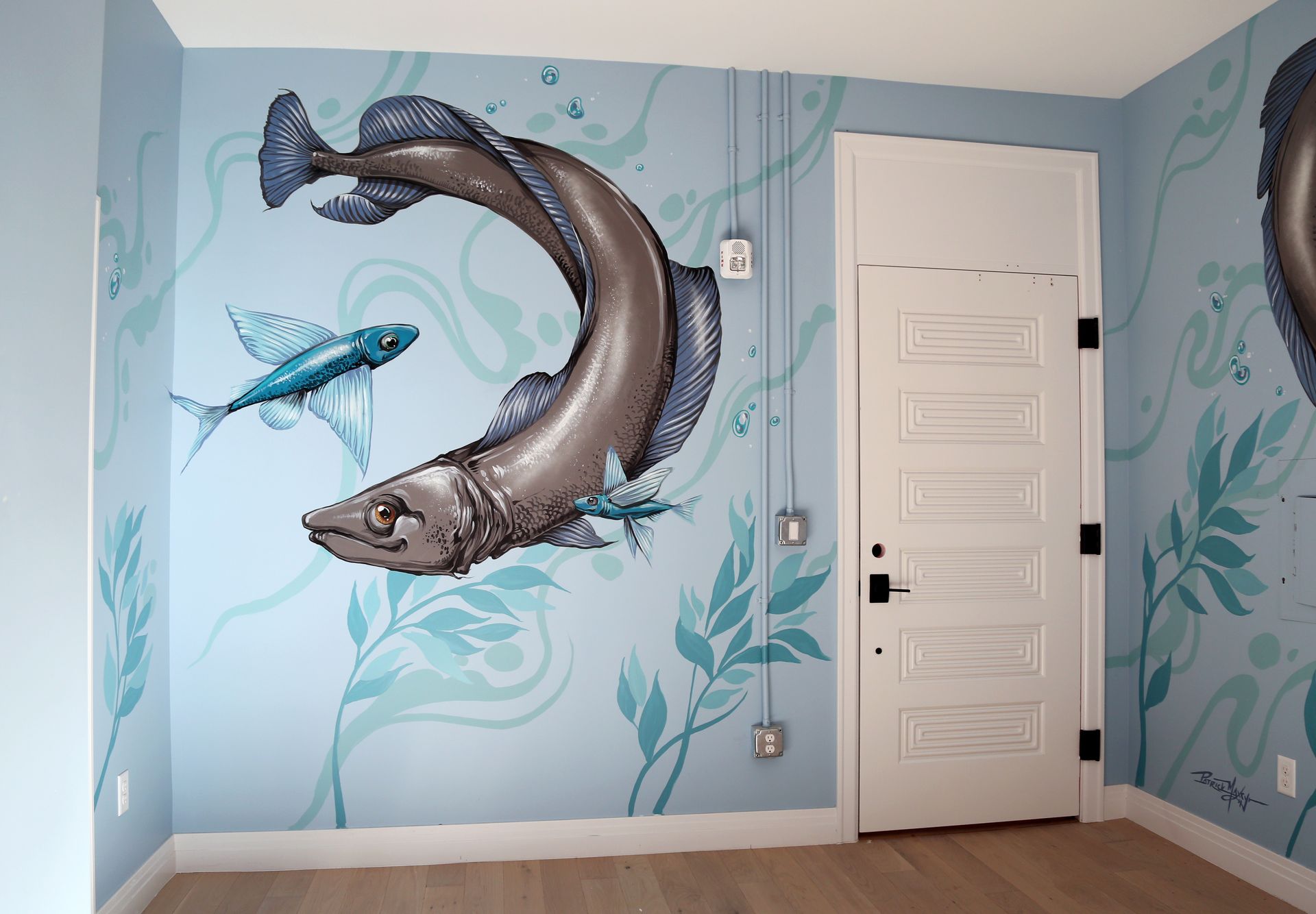 Murals of a leaping fish and blue aquatic plants on a light blue wall beside a white door.