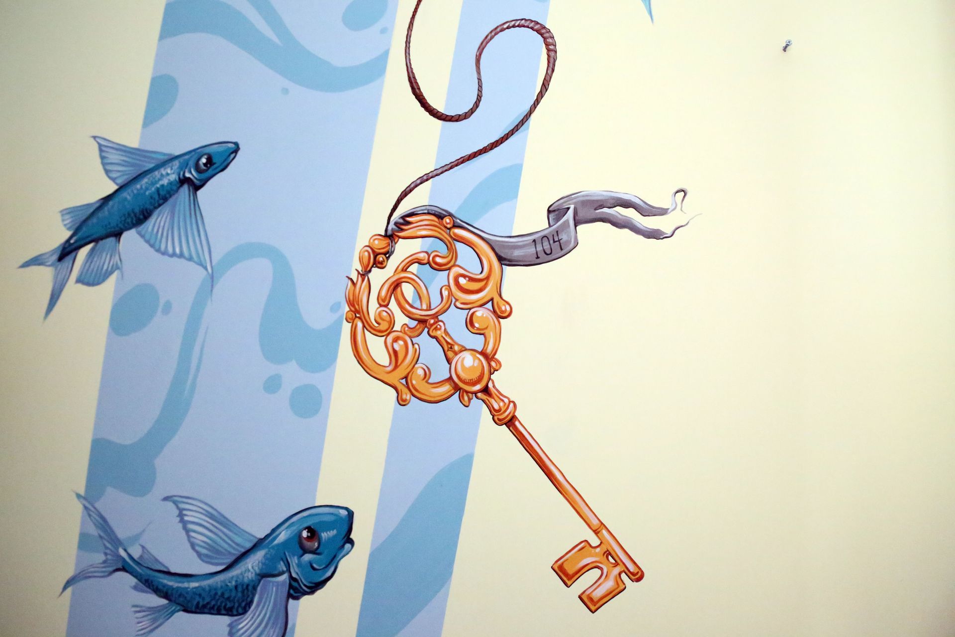 Blue birds and an ornate orange key hanging on a pale background, with a rope loop above.