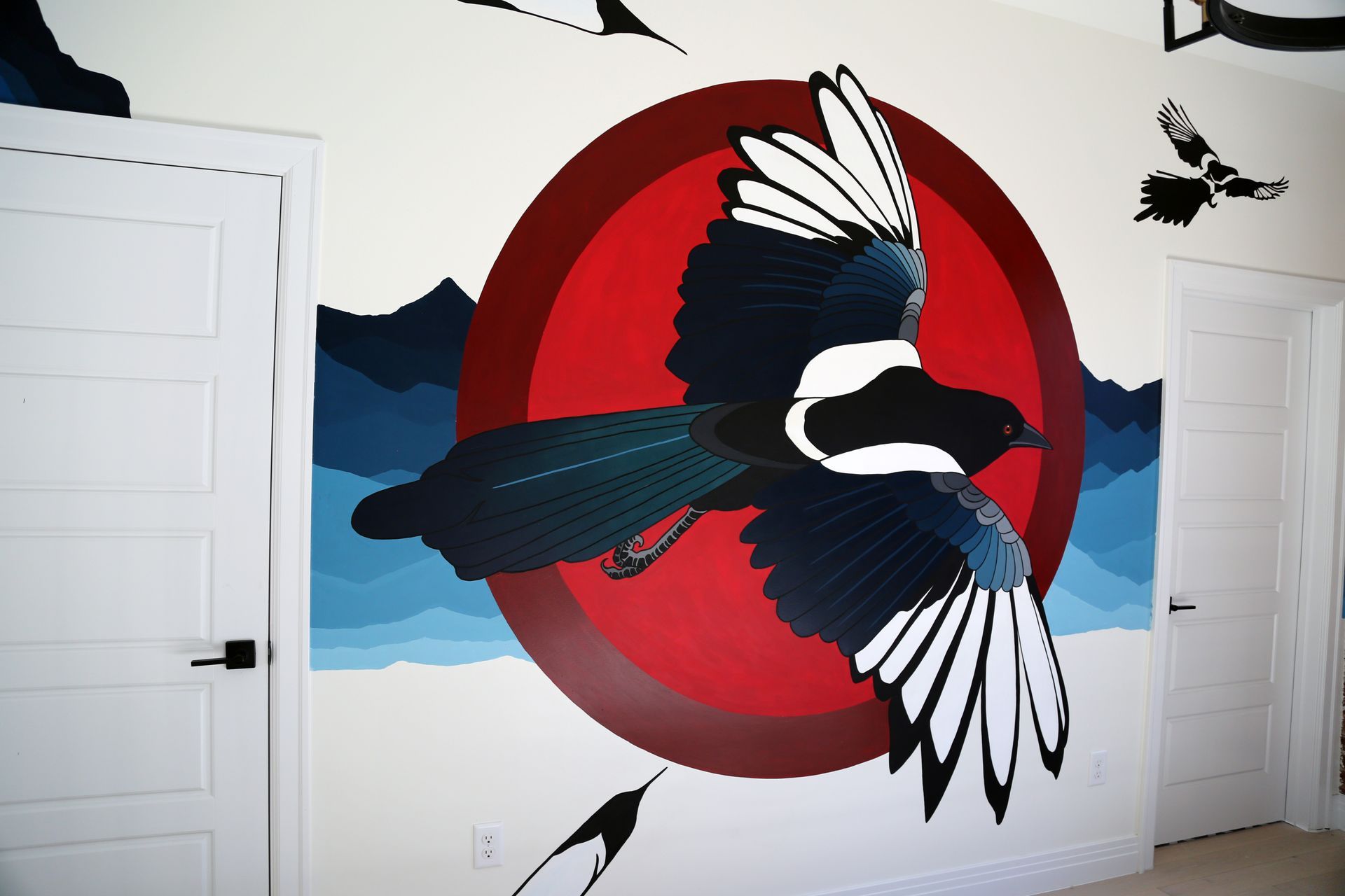 Bird mural with a black-and-white bird flying across a red circle on a white wall