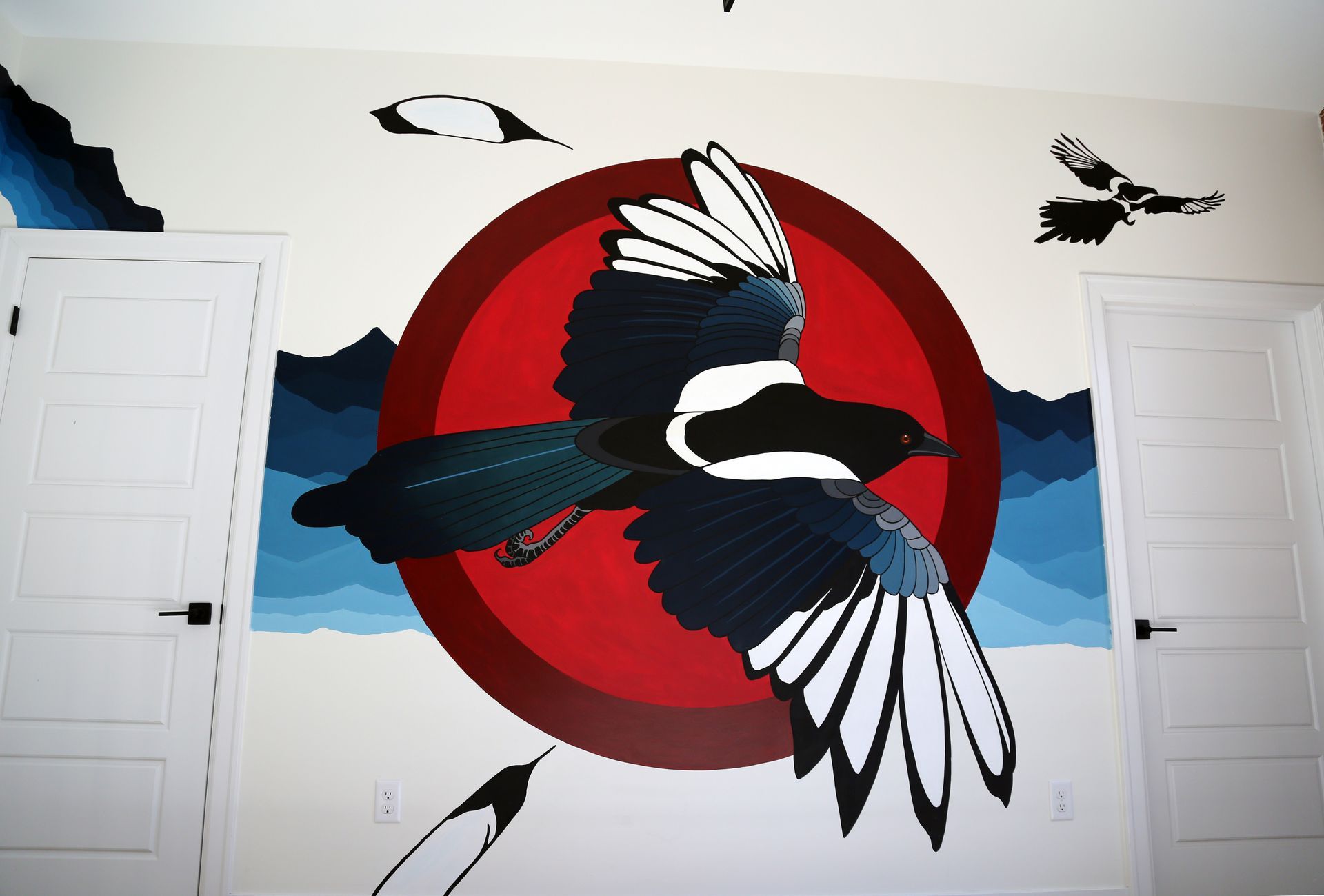 Bird mural with a red sun, black-and-white birds in flight, and white doors on a wall