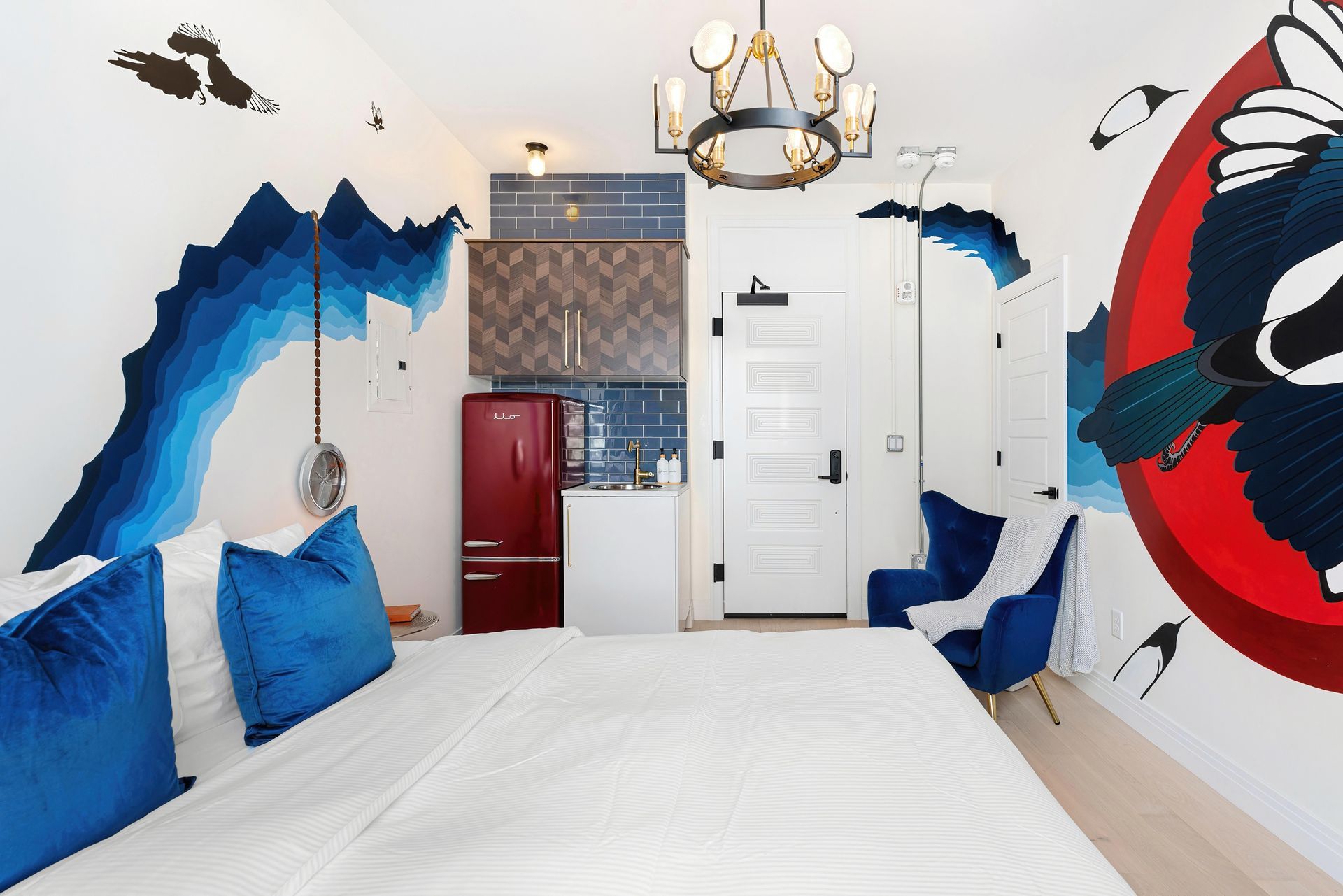 Blue mountain-themed bedroom with white bed, red cabinet, and chandelier on the ceiling