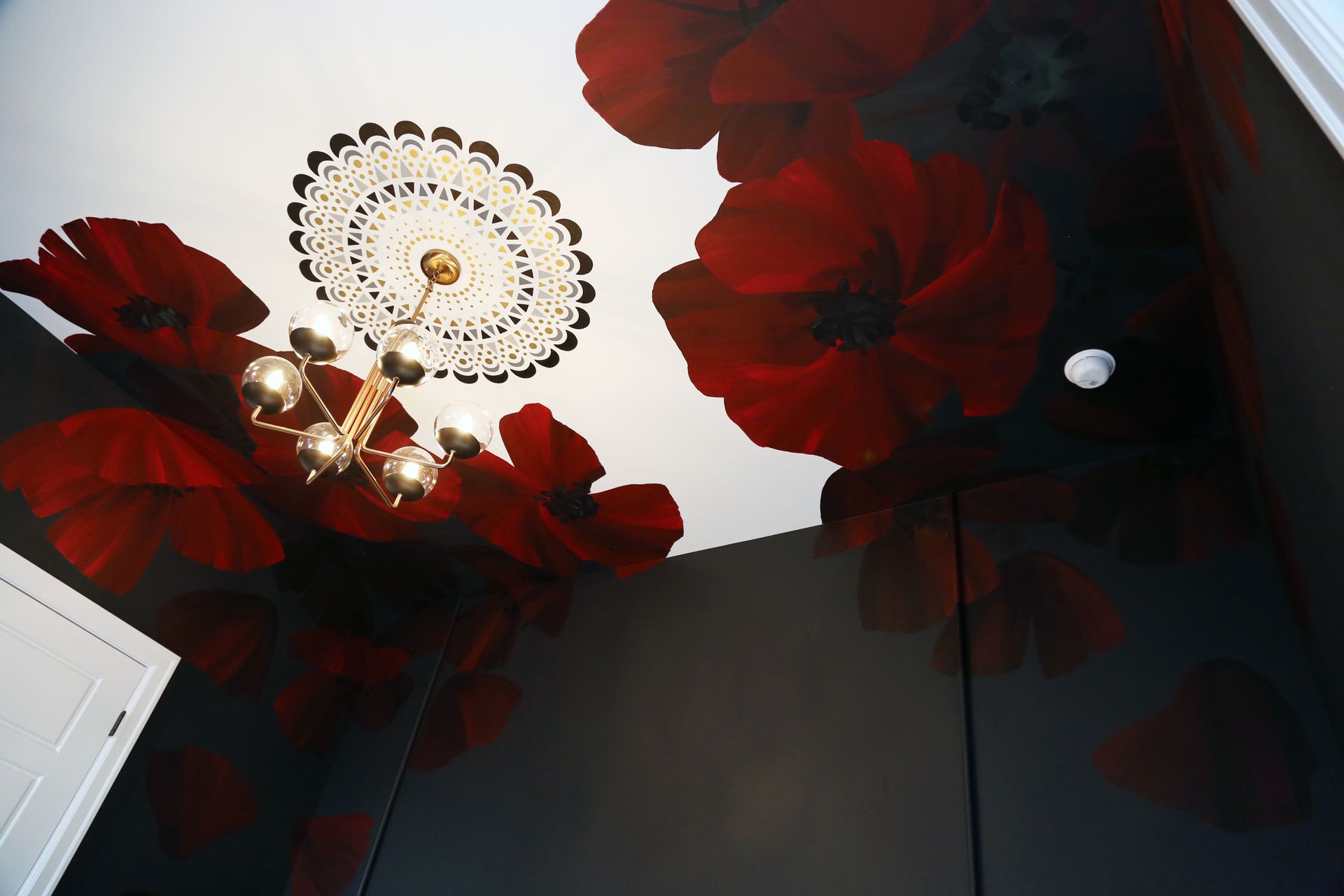 Red floral ceiling decor with a chandelier in a dimly lit room