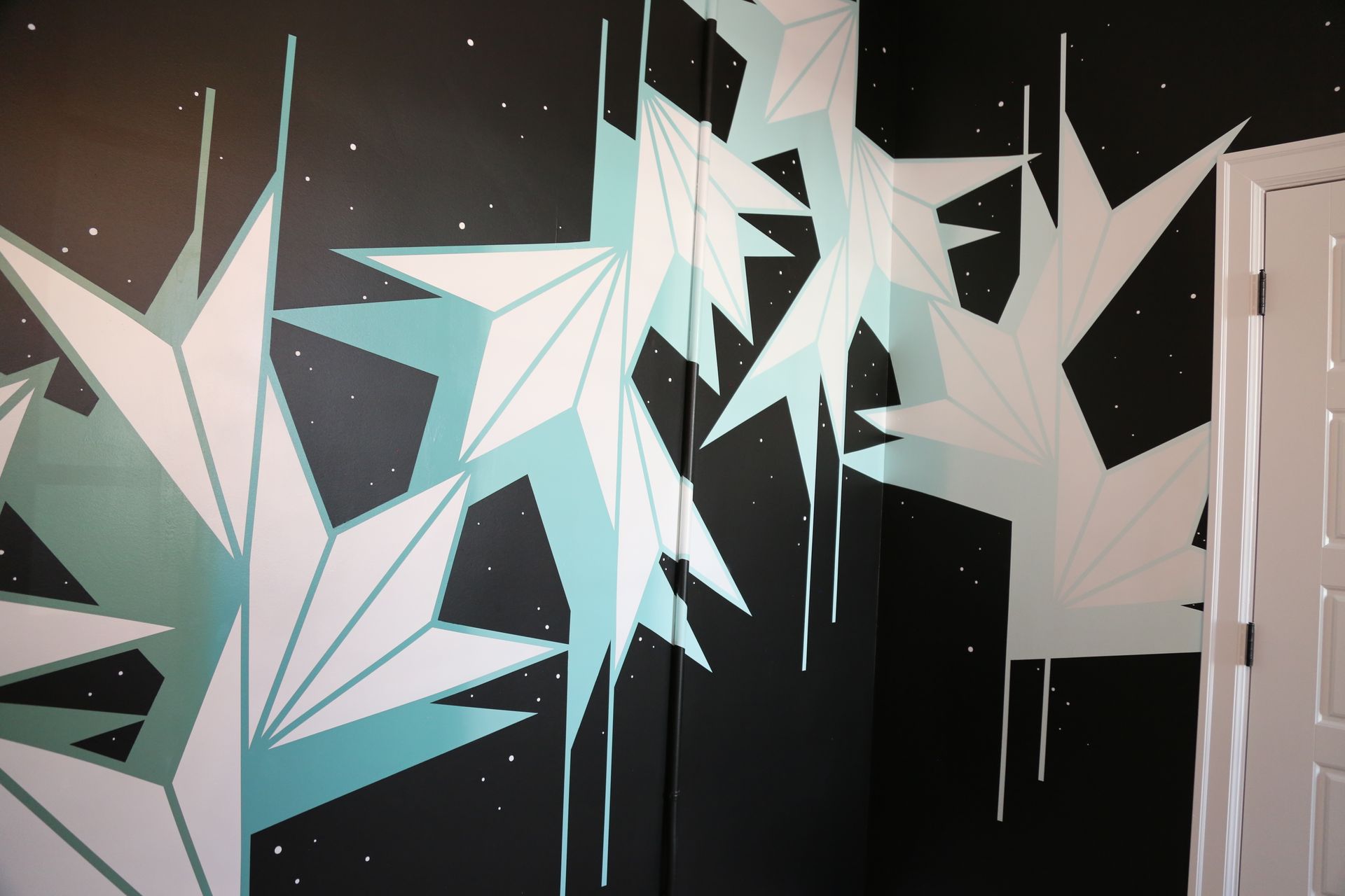 Abstract geometric mural with white and teal angular shapes on a dark background