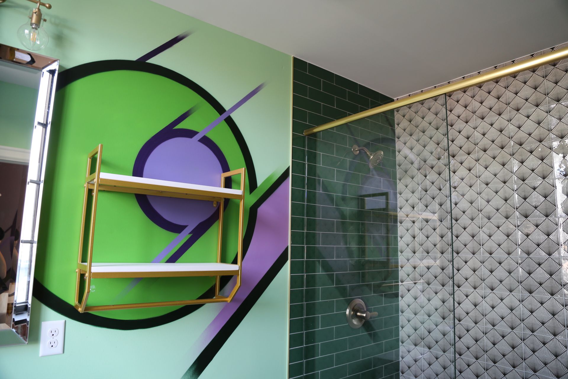 Colorful bathroom with a green wall, purple circle mural, towel shelf, and patterned tile shower area