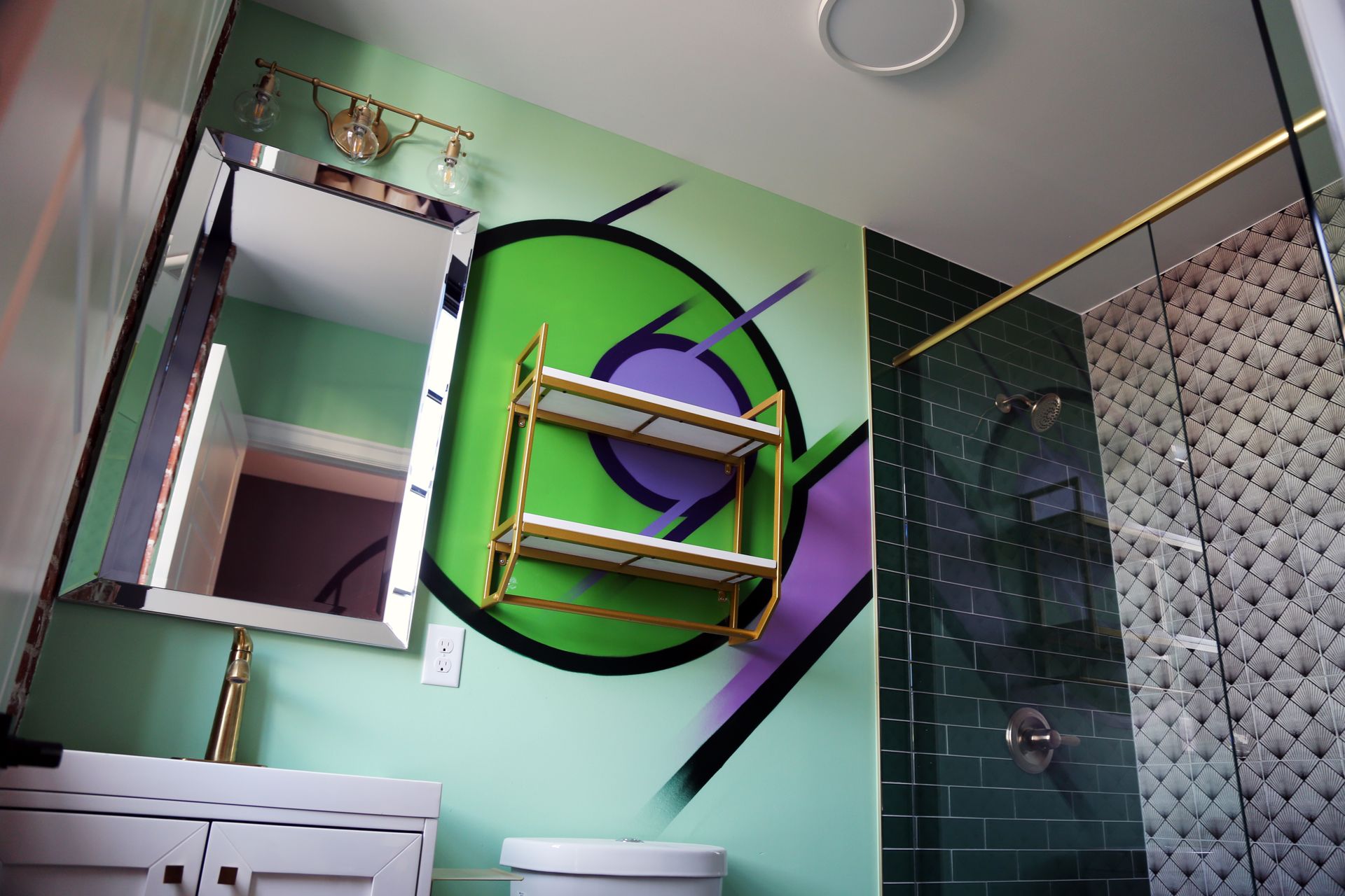 Modern bathroom with colorful abstract wall art and gold-framed mirrors above the sink