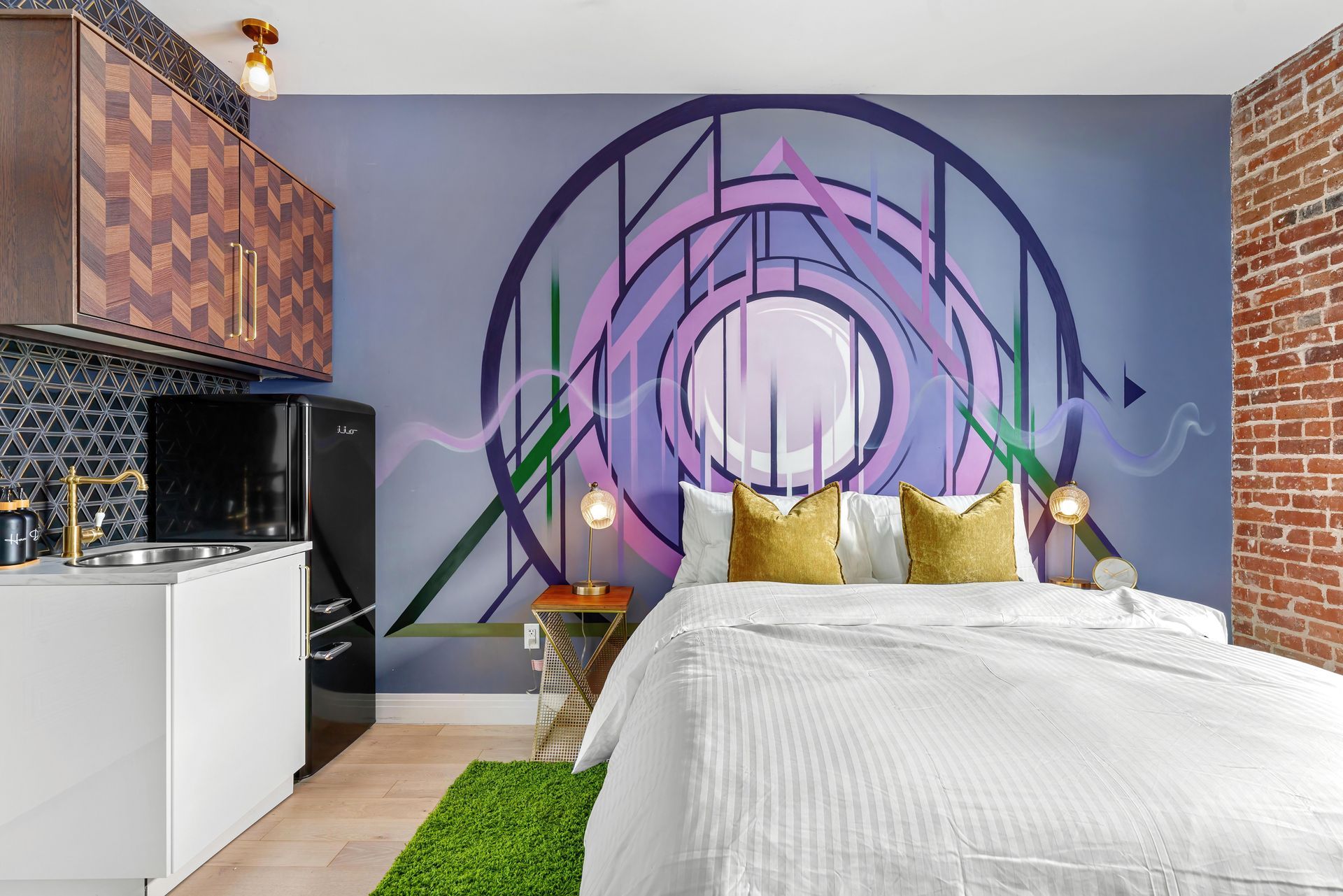 Colorful bedroom with purple wall mural, white bed, green rug, and exposed brick accents