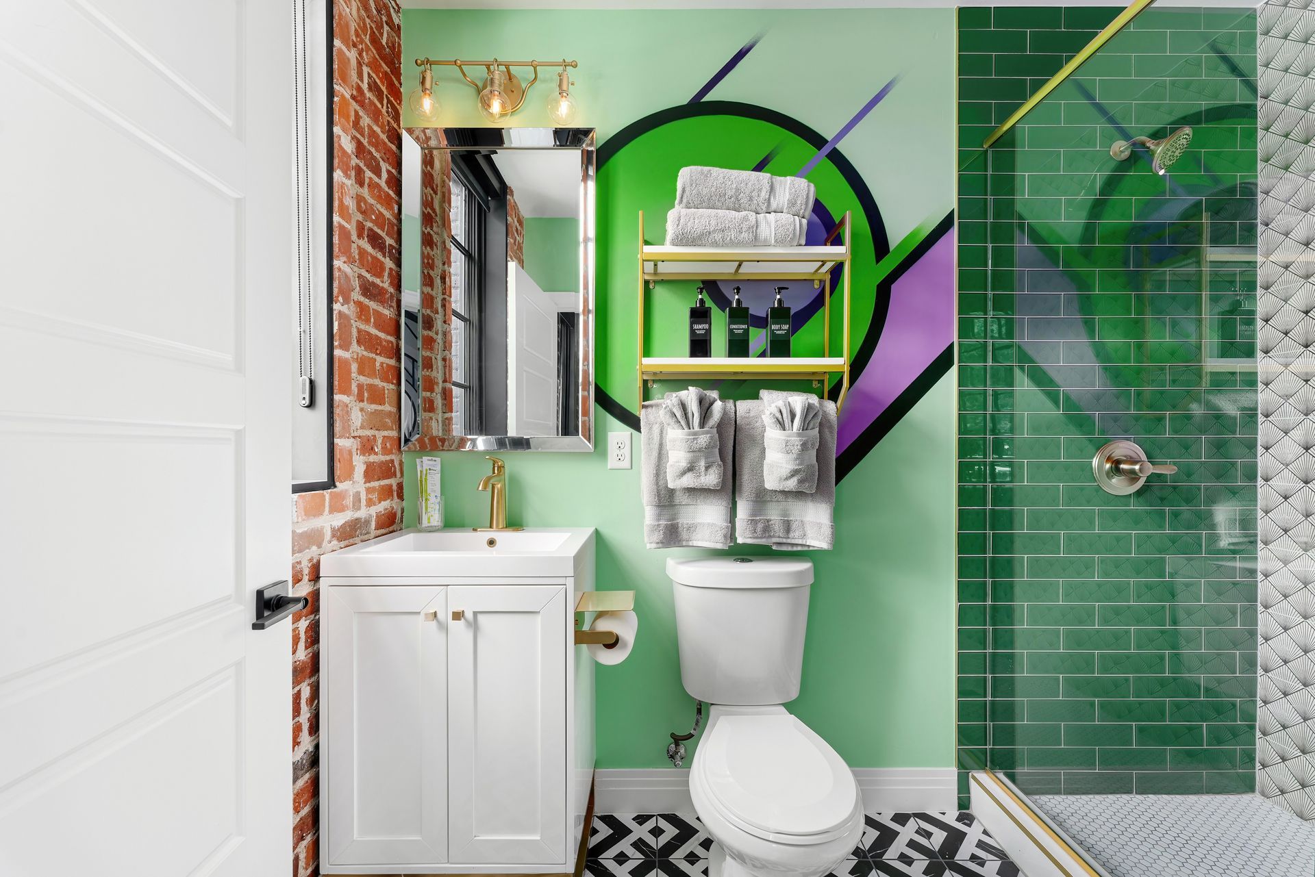 Compact bathroom with white vanity, toilet, green-tiled shower, and bold green-purple mural wall.