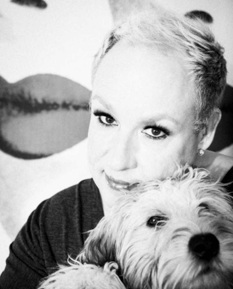 Black-and-white portrait of a person holding a fluffy dog close to their face.