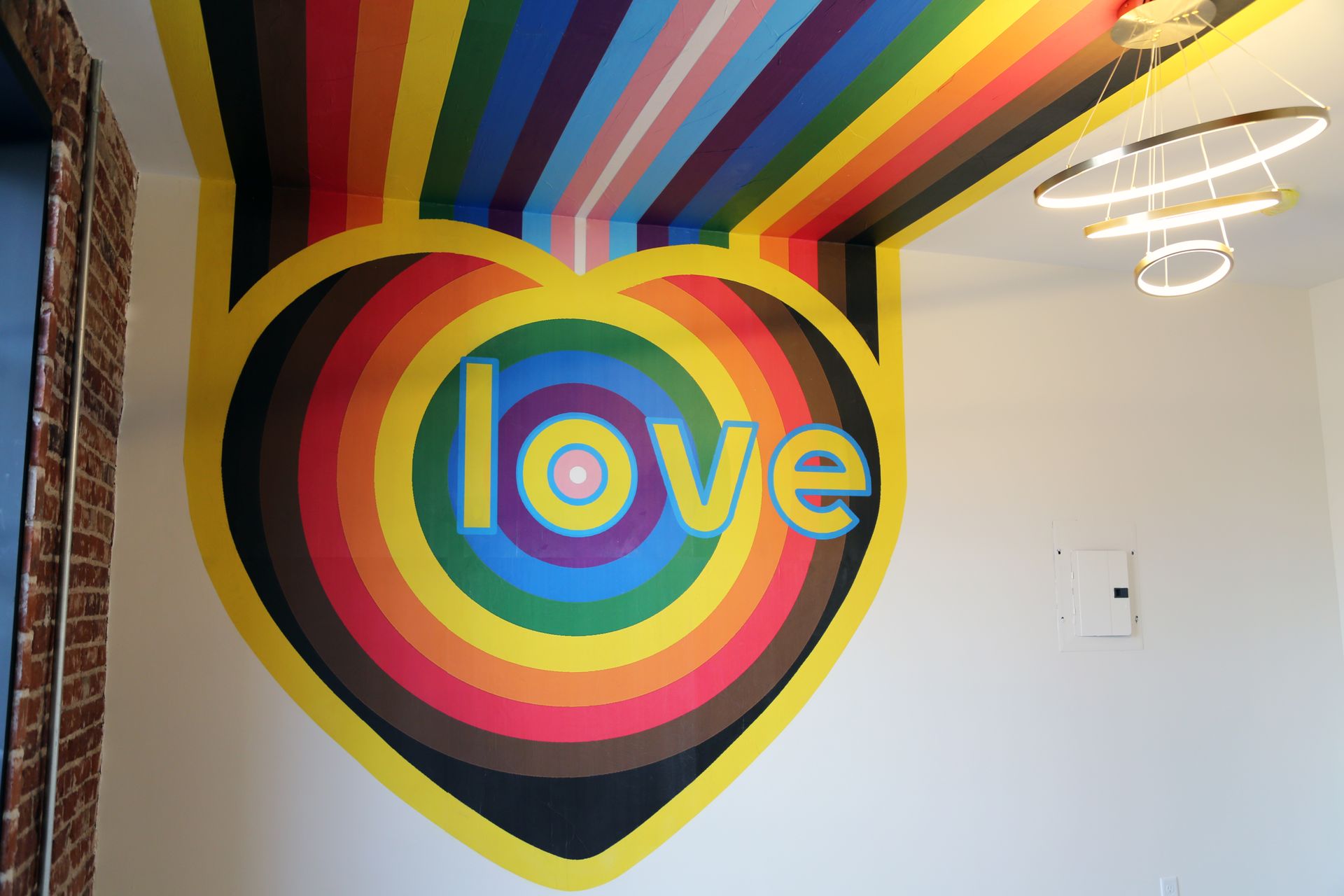 Colorful rainbow mural with concentric circles and the word “love” on a wall