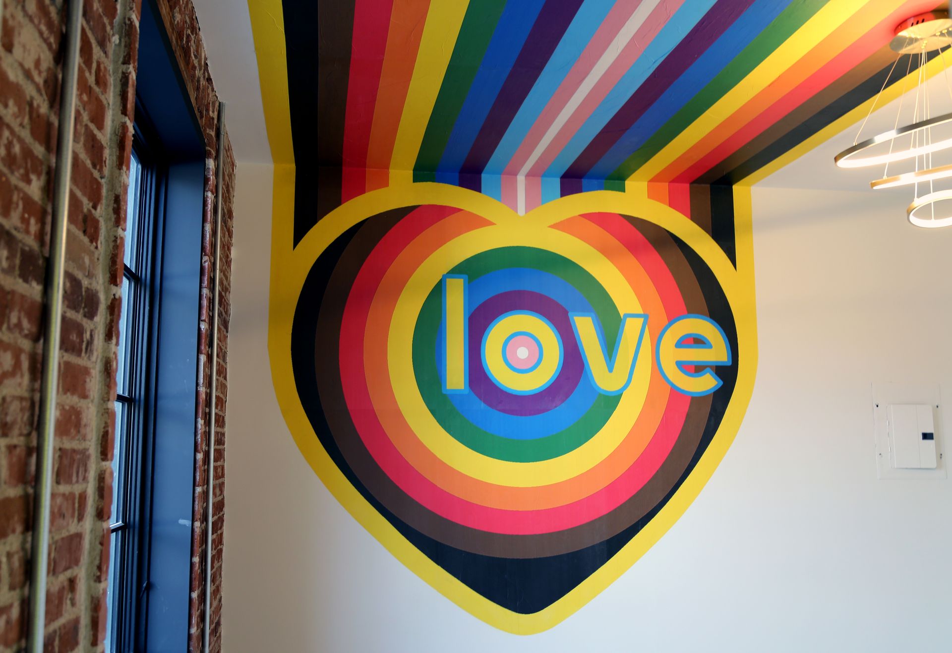 Rainbow-painted wall with concentric circles and the word “love” in a hallway