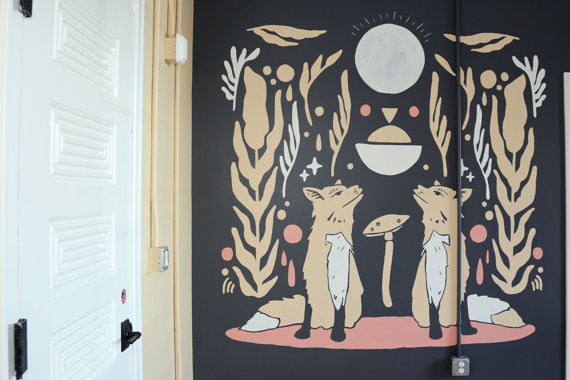Wall mural with two deer under a moon, framed by gold leaves on a dark background.