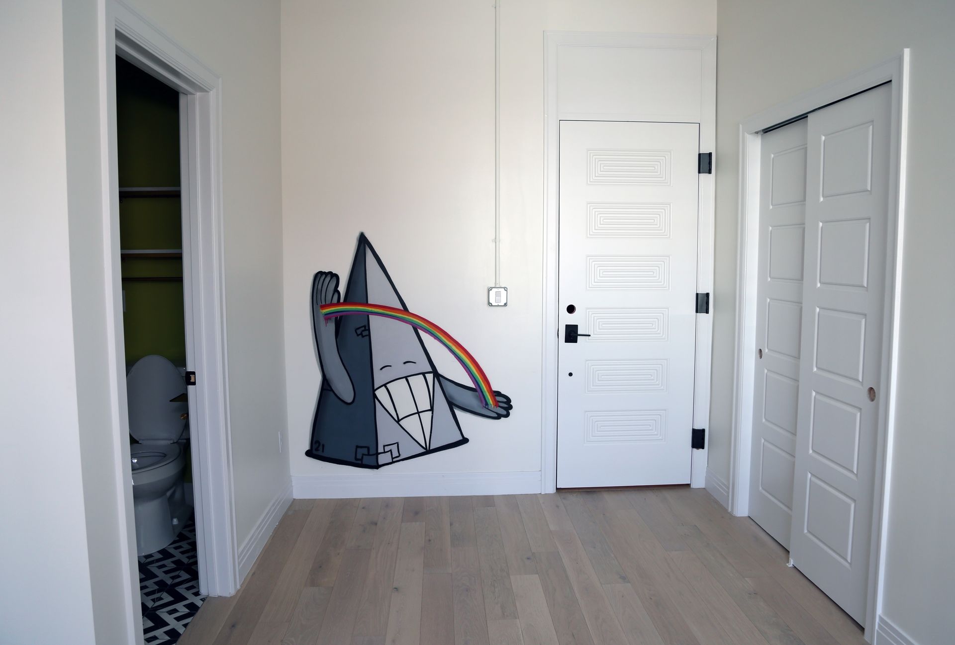 White hallway with doors, open closet, and a folded toy cart against the wall.
