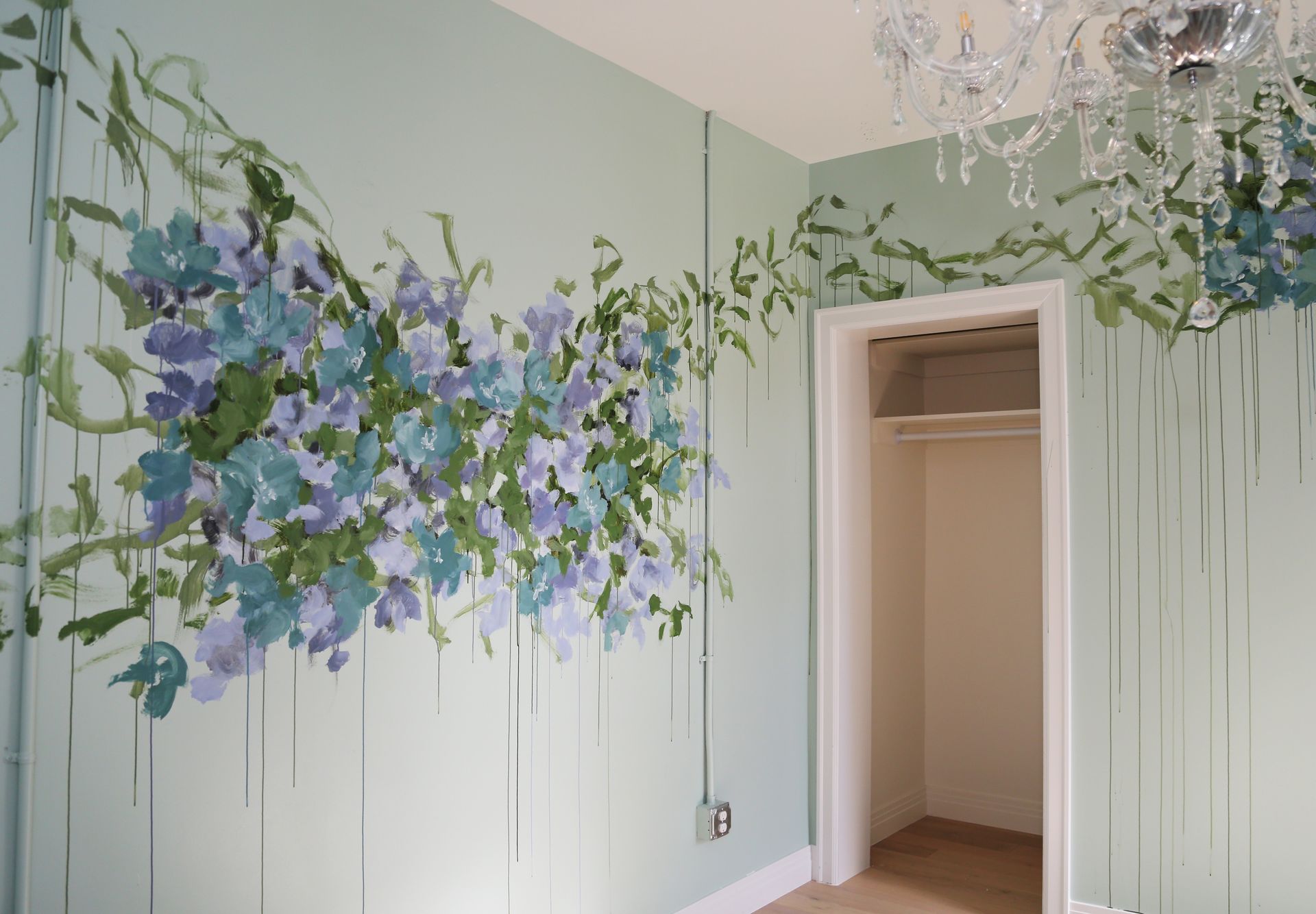 Mint-green wall mural with purple and blue flowers and an open doorway in a room