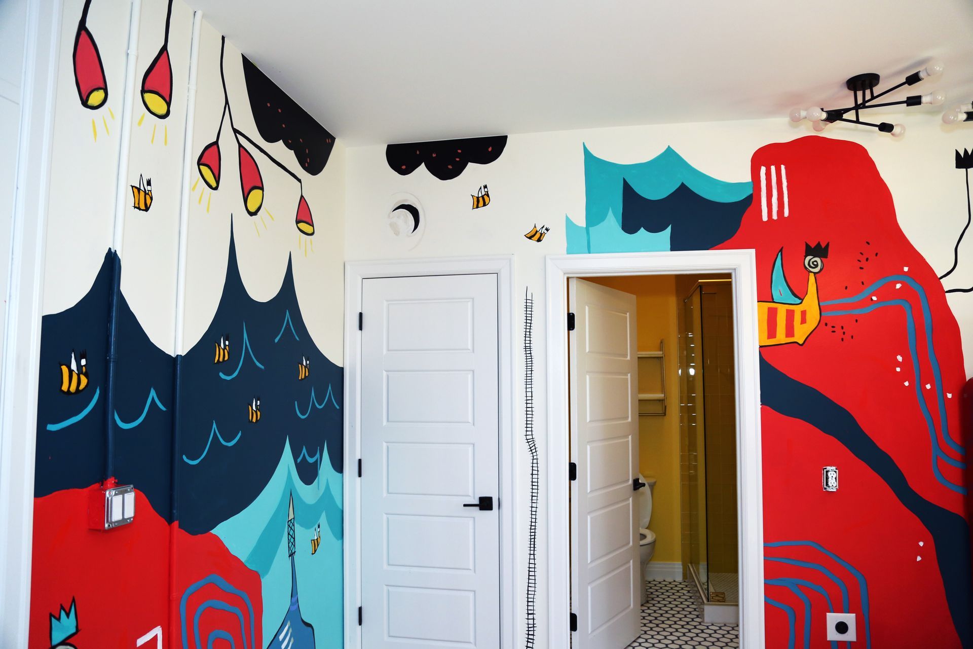 Colorful mural-covered room with red, blue, and black wall art around a white door and open doorway