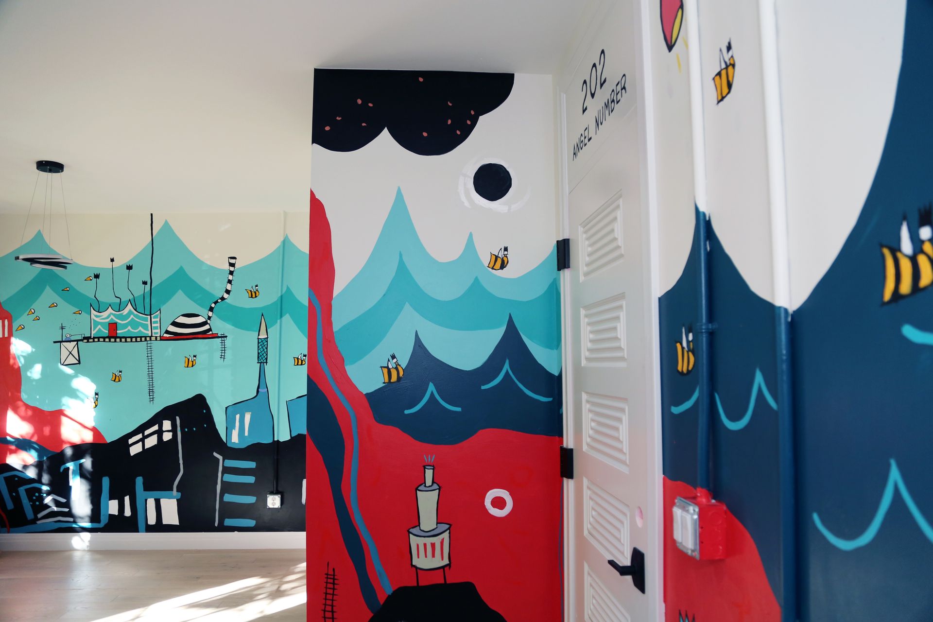 Colorful underwater-themed mural in a hallway with waves, fish, and ocean motifs on white walls