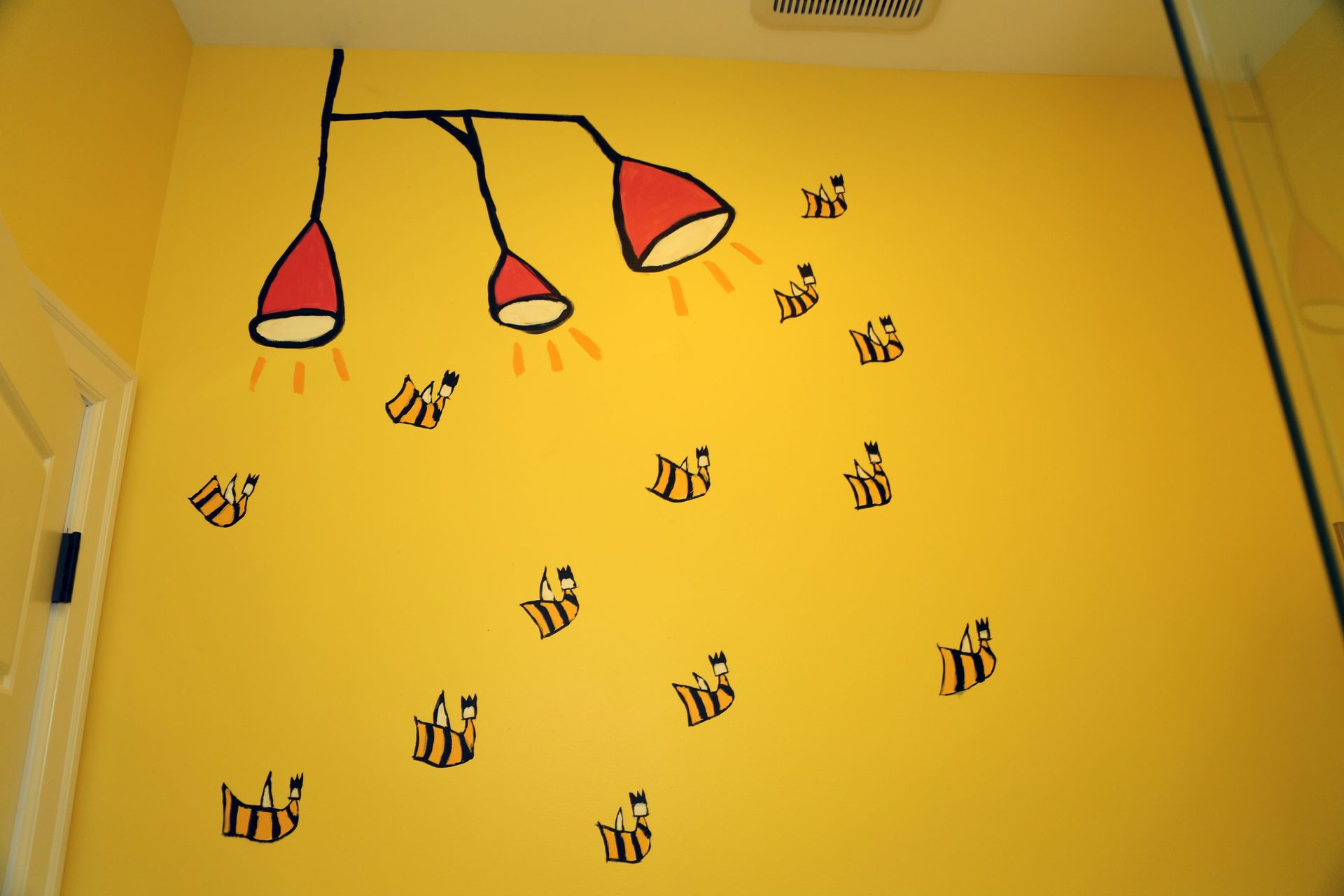 Yellow wall with black music note decals and three red hanging lamps.