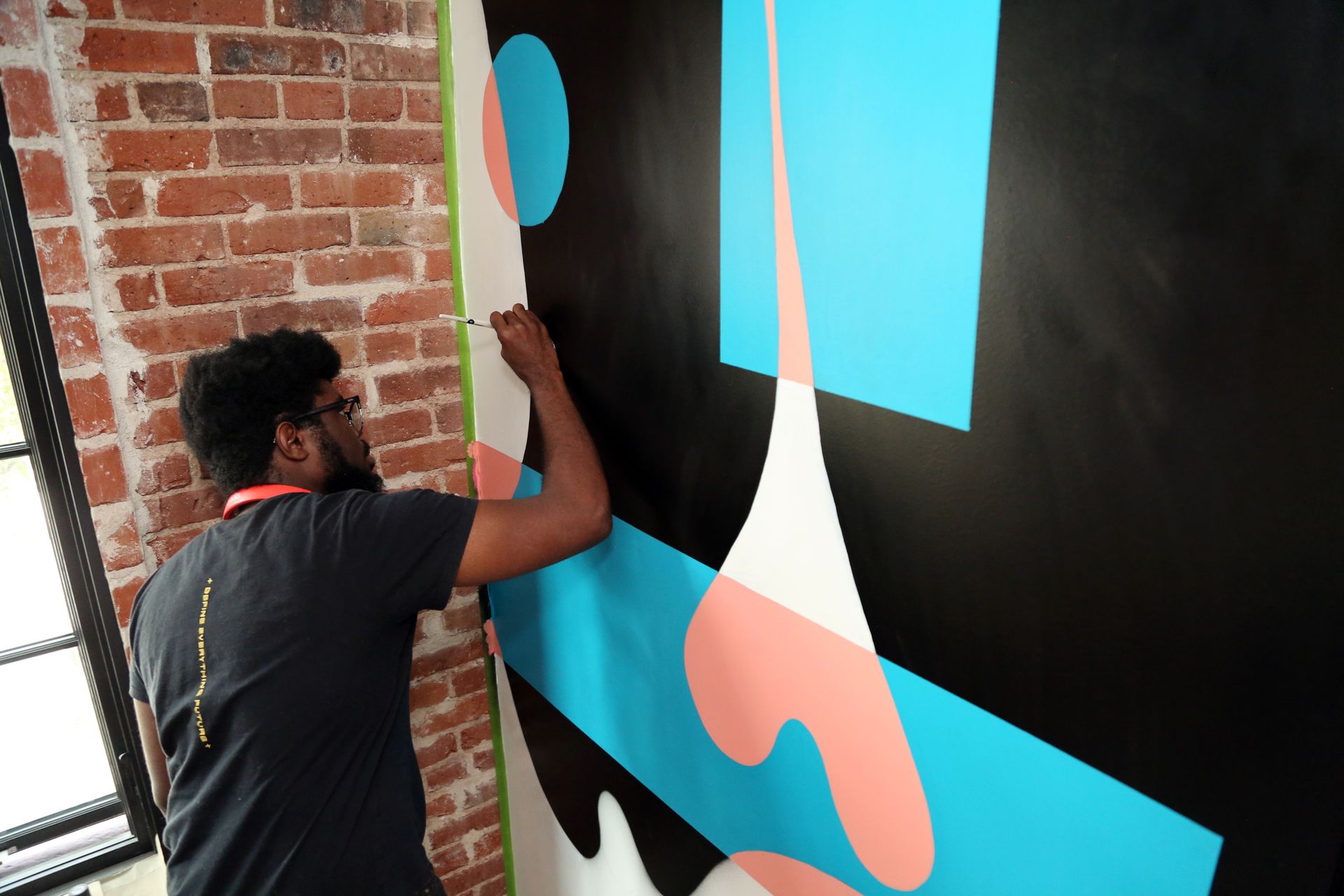 Person painting a colorful mural on a brick wall indoors