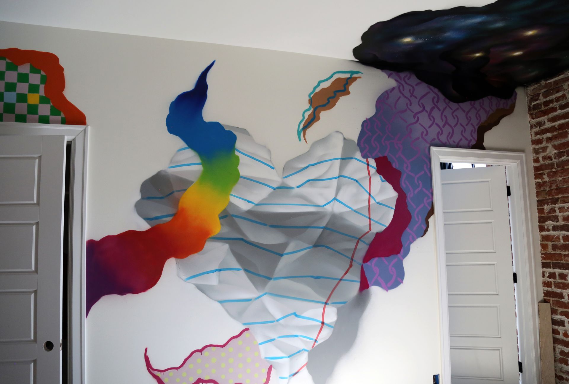 Colorful abstract mural on a wall between two doors, with blue contour lines and cloud-like shapes