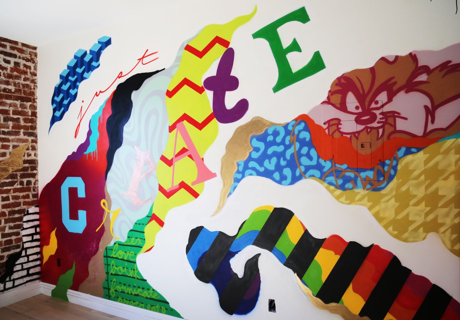Colorful abstract mural with large letters, zigzag patterns, and a sleeping cat illustration on a wall