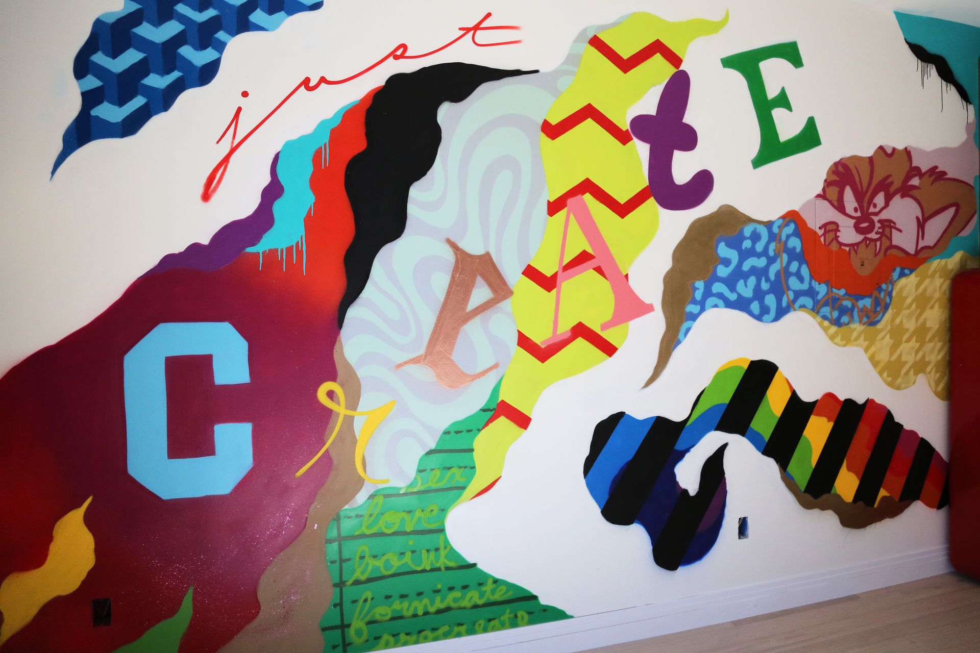 Colorful abstract mural with layered letters and wavy shapes on a white wall