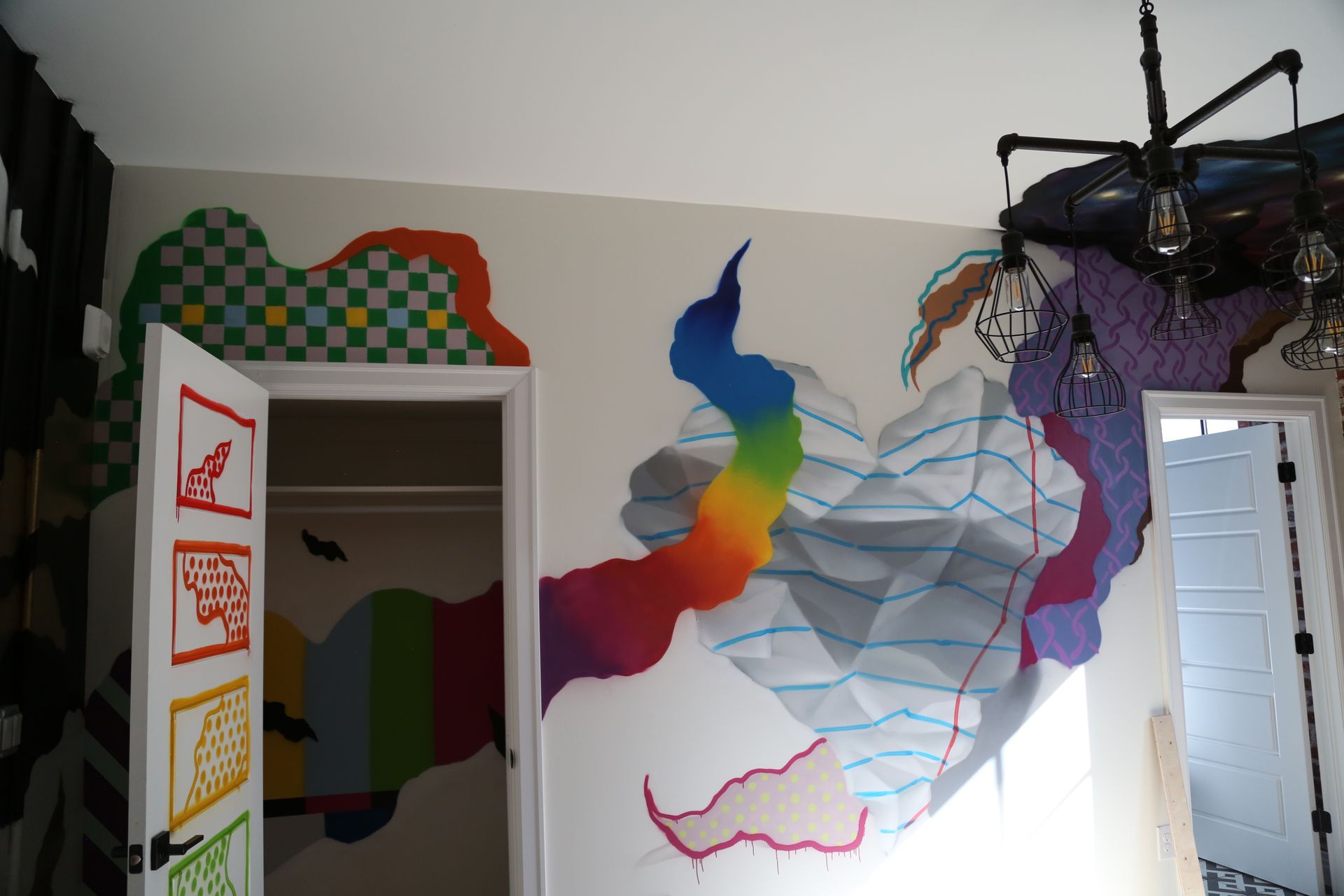 Colorful mural of a blue-and-rainbow bird on a white wall beside a doorway