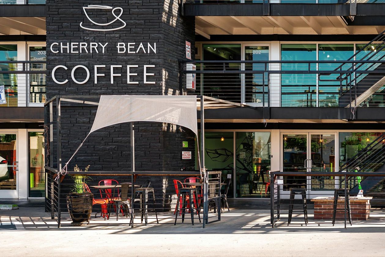 Cherry Bean Coffee storefront with outdoor seating and glass facade in a modern building