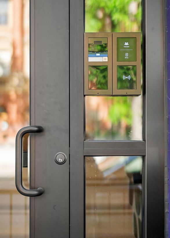 Glass door with a black handle and a contactless access keypad mounted beside it