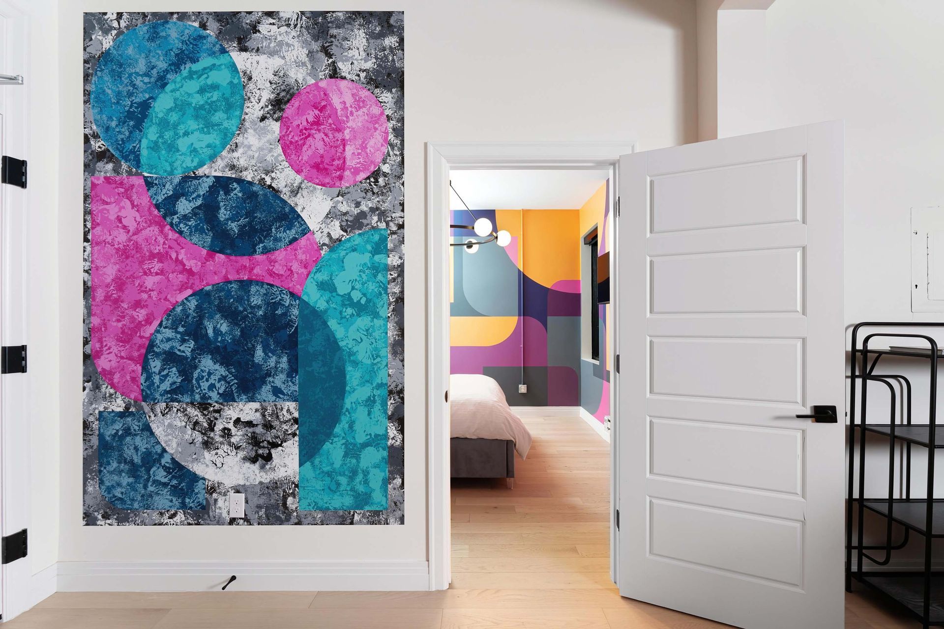 Bright abstract wall mural with teal, pink, and blue circles in a modern room with an open white door