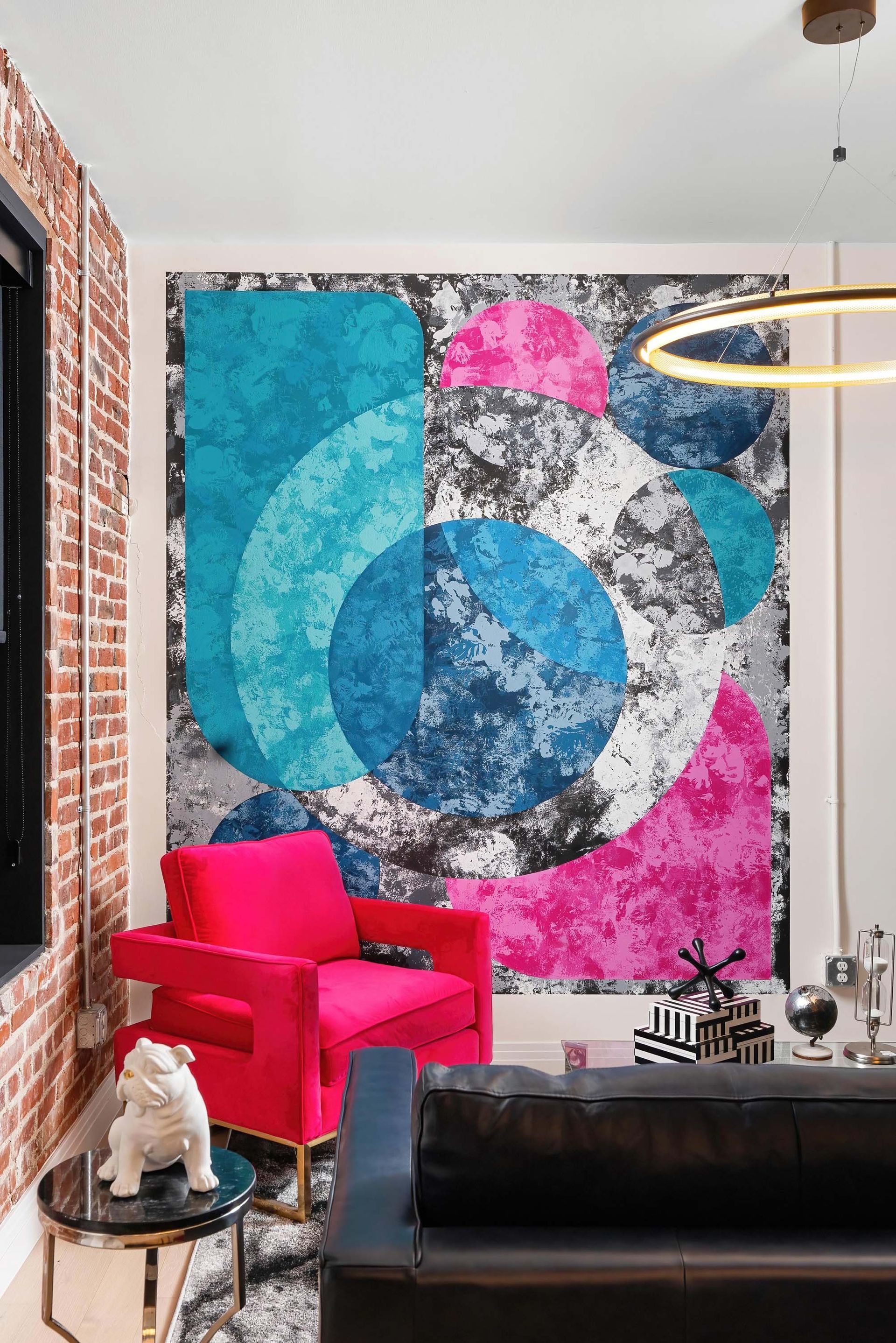 Colorful abstract wall mural in a modern living room with a red chair and black sofa.