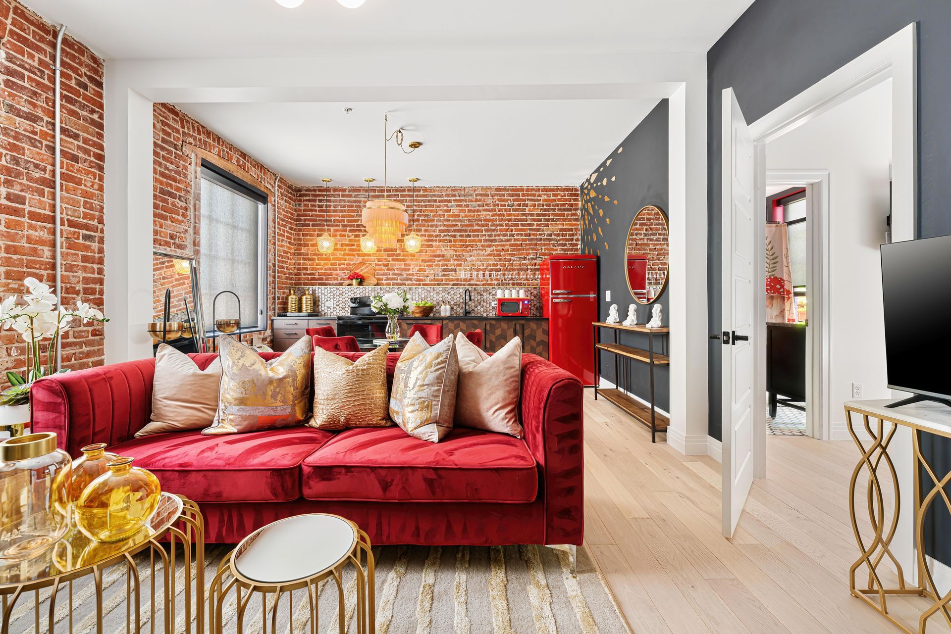 Bright living room with red velvet sofa, exposed brick wall, and modern decor