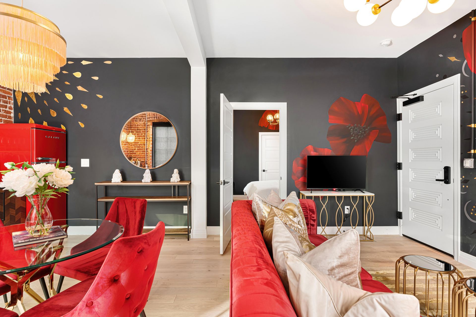 Modern living room with red sofas, black walls, white door, and gold accents