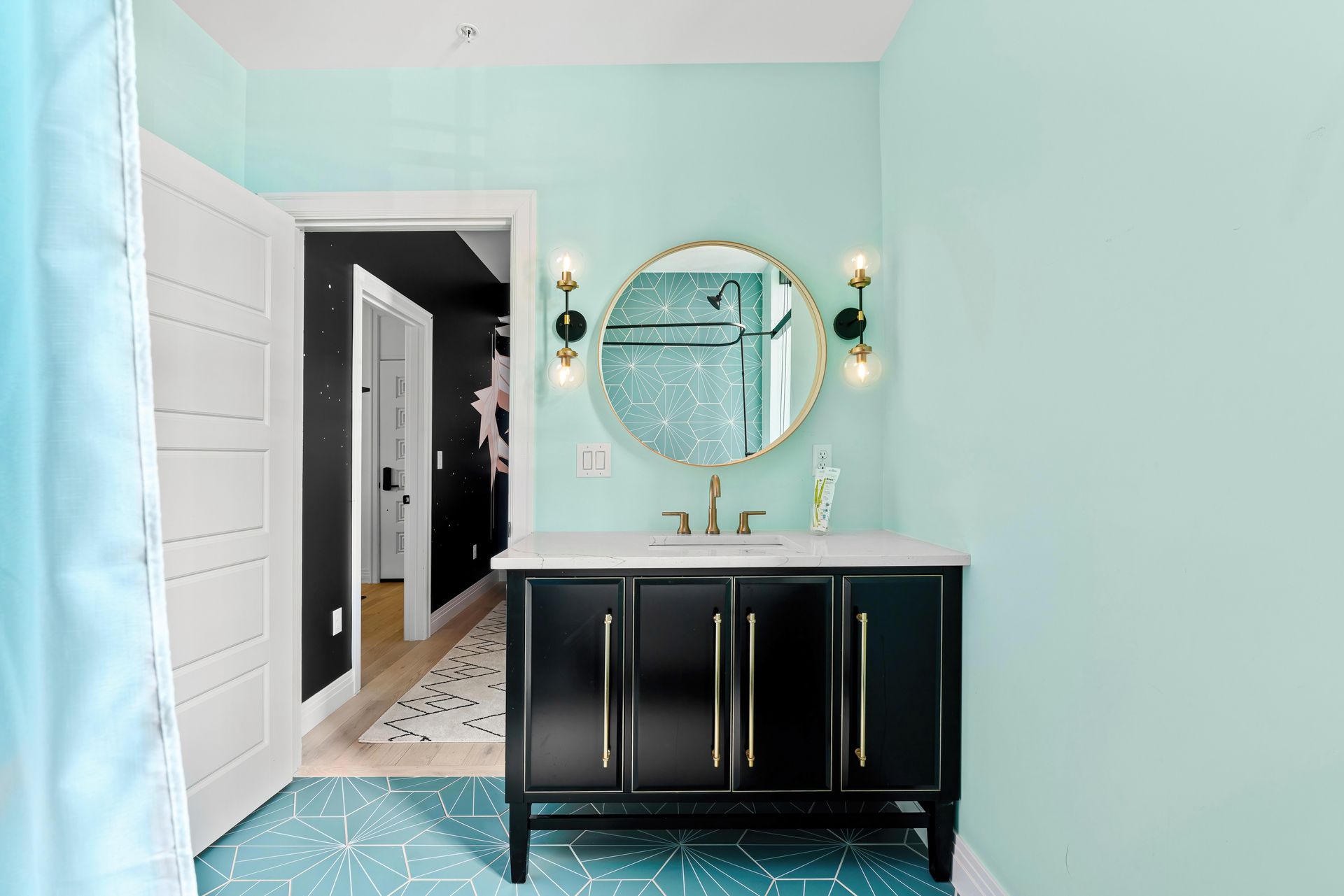 Mint bathroom with black vanity, round mirror, and white double doors