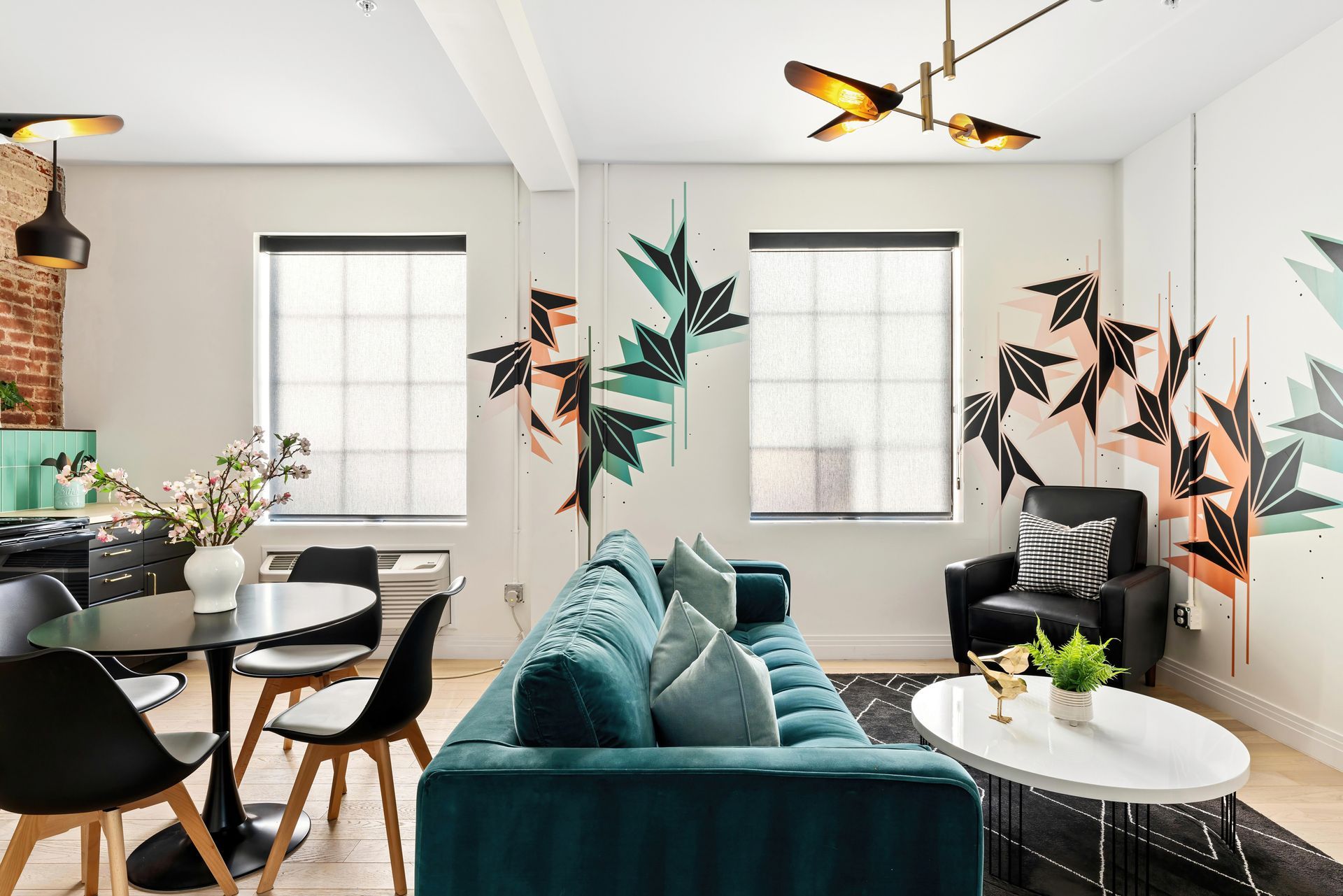 Stylish living room with teal sofa, black chairs, white table, and butterfly wall art by bright windows