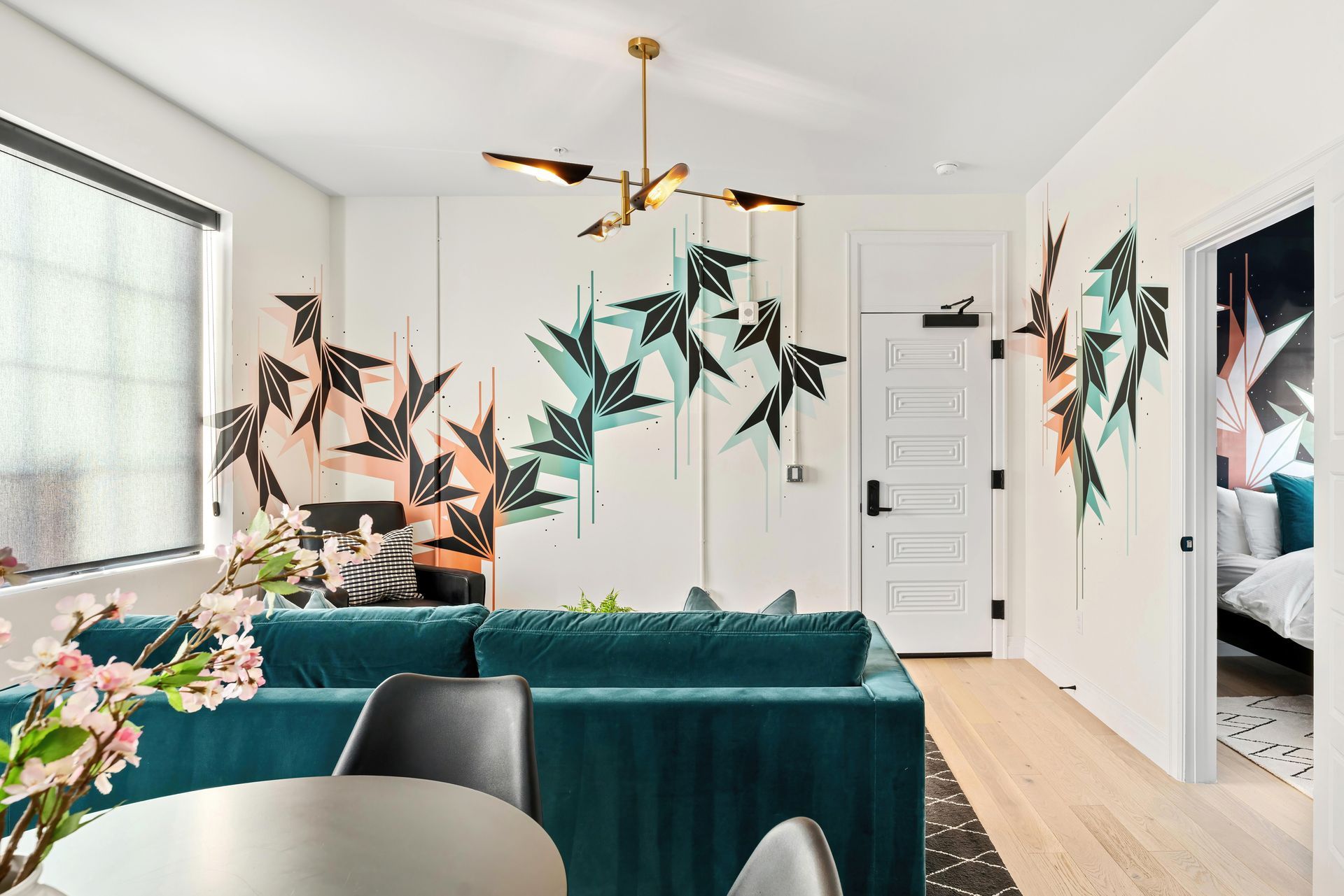 Bright modern living room with teal sofa, black chairs, and colorful abstract bird wall art