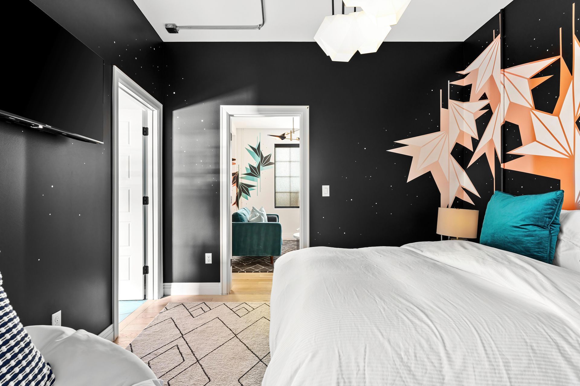 Black-and-white bedroom with a bed, teal pillows, and geometric wall art