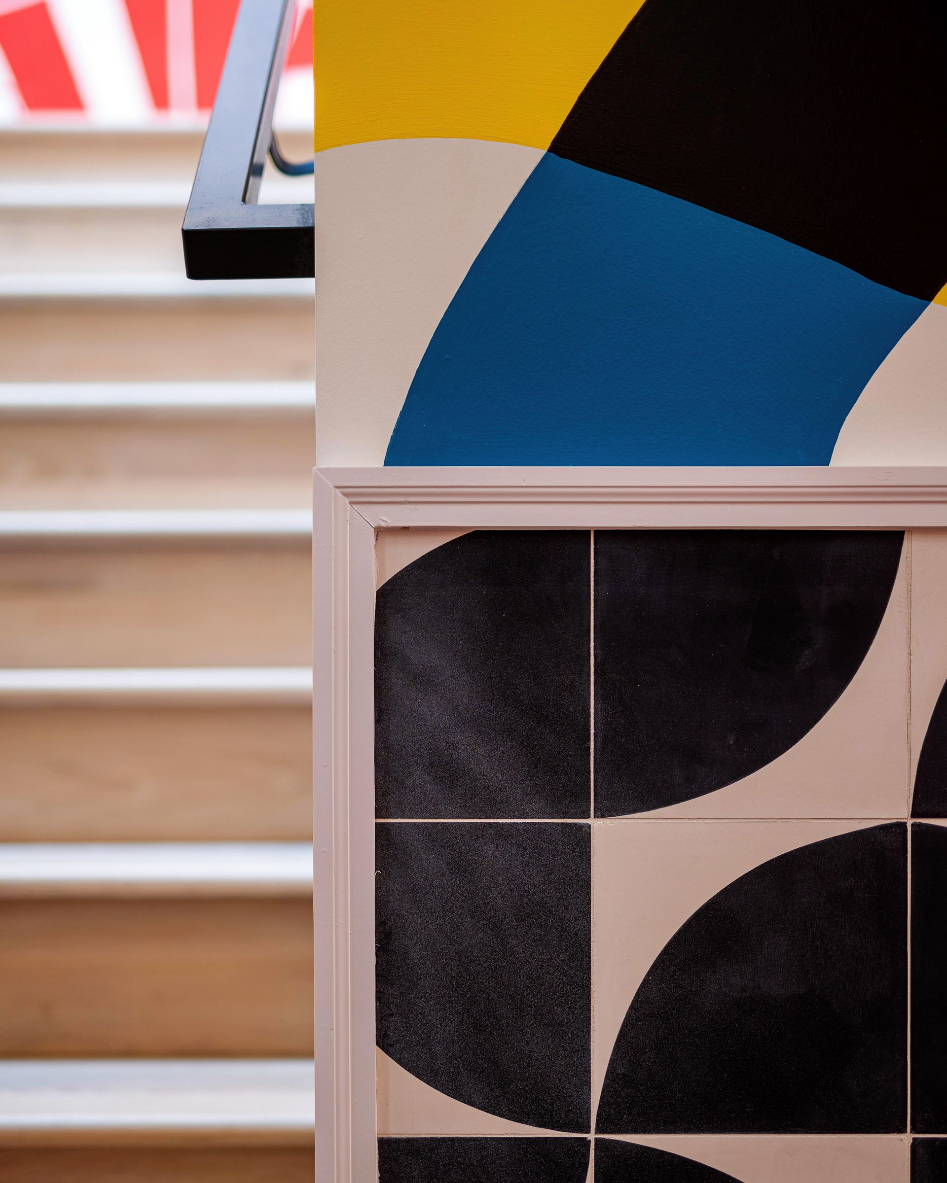 Abstract geometric wall art with black, blue, and beige shapes above a framed pattern