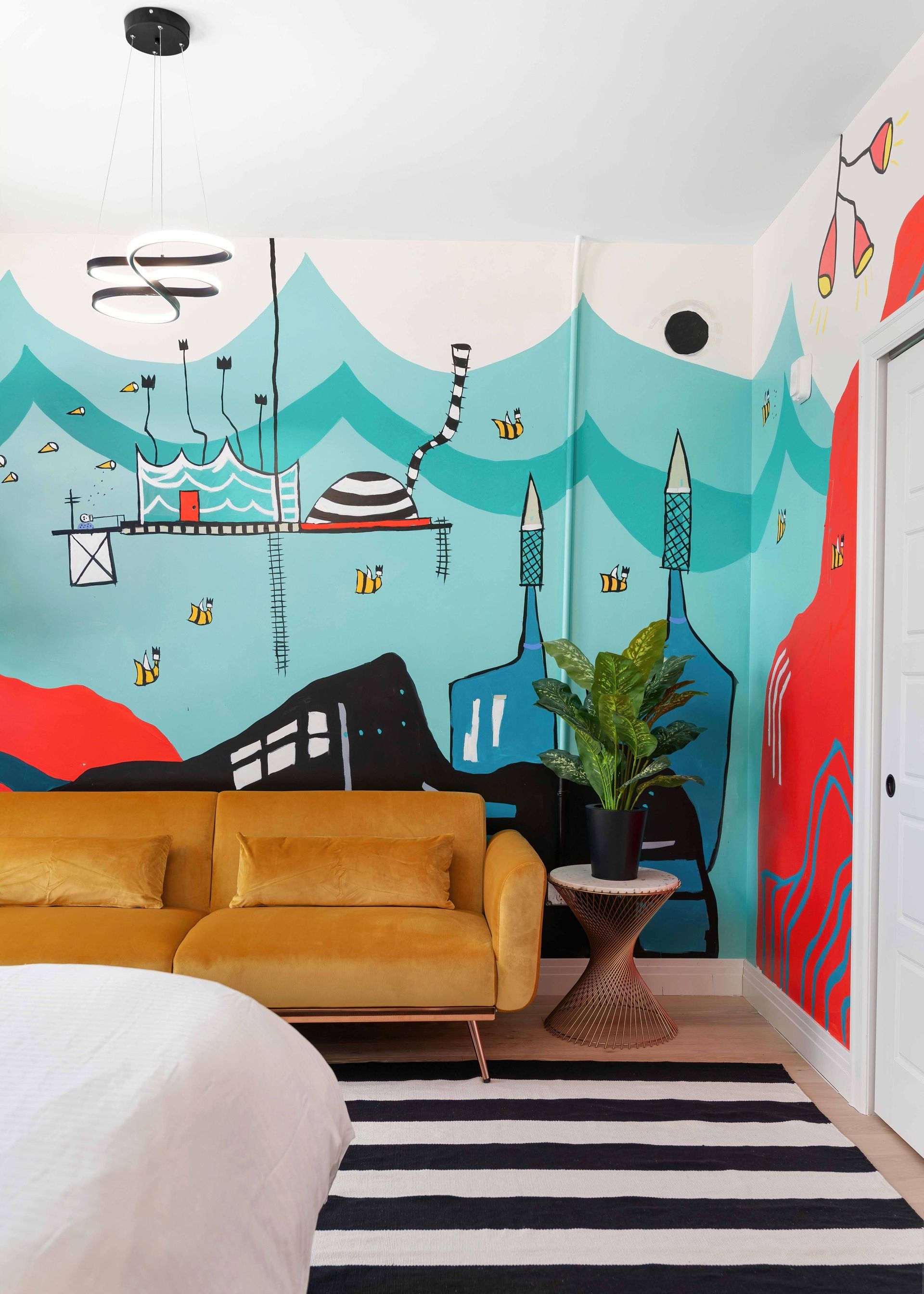 Modern living room with mustard sofa, black-and-white rug, and colorful mural wall art