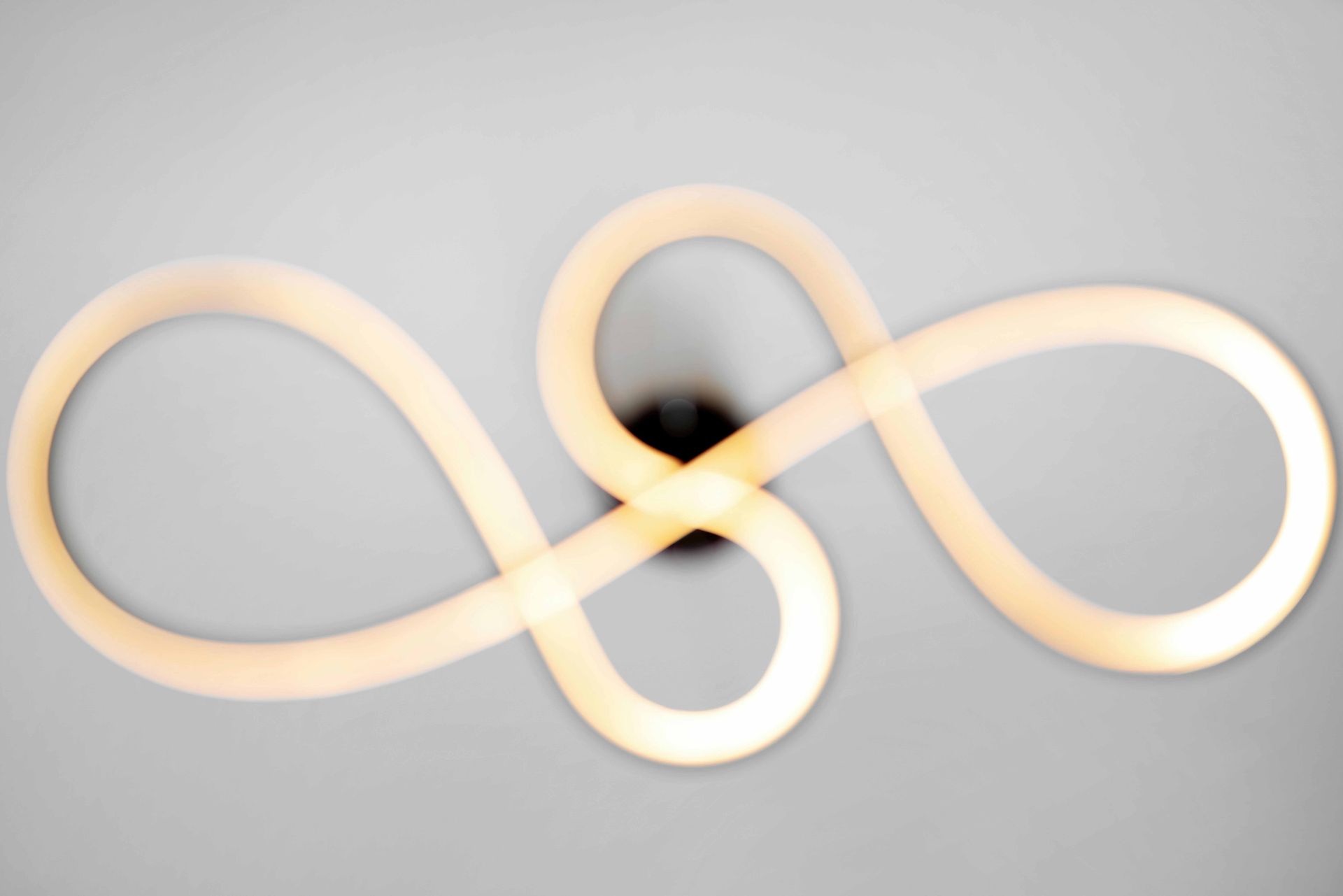 Abstract beige infinity-shaped light on a gray background